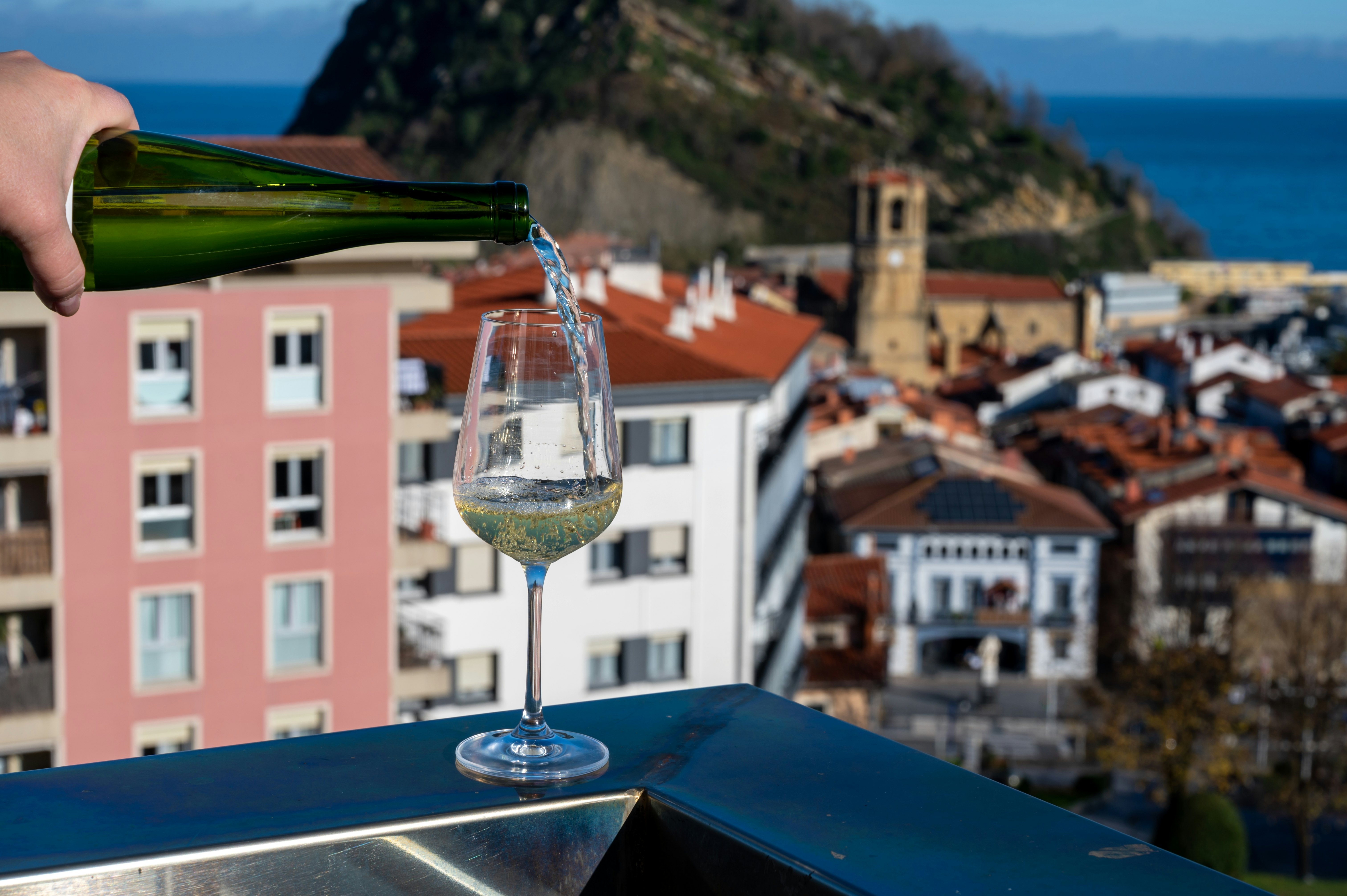 A glass of a wine on a balcony with a view of the old town in the background.