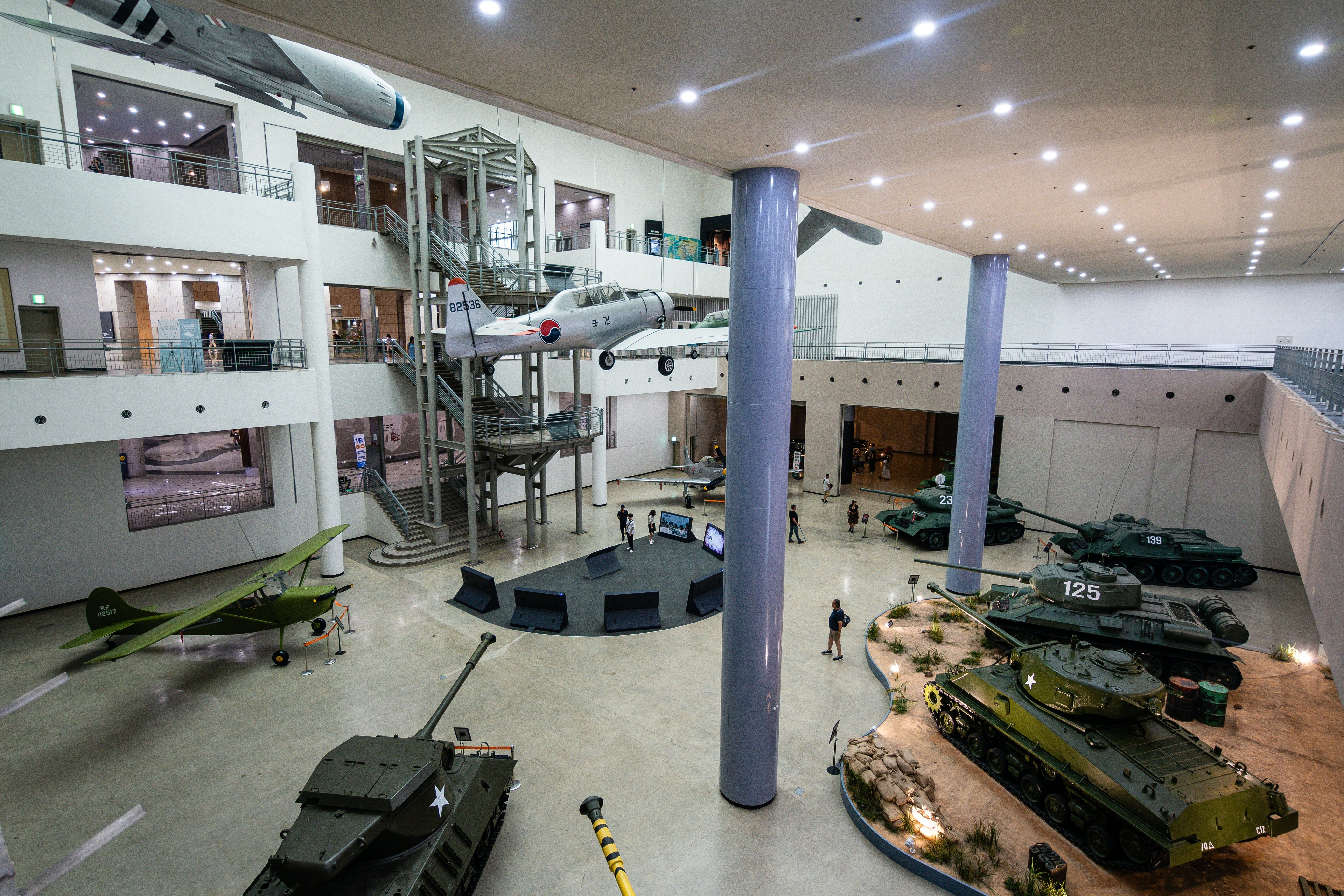 Tanks, warplanes and other military matériel is on display in a huge gallery of a museum.