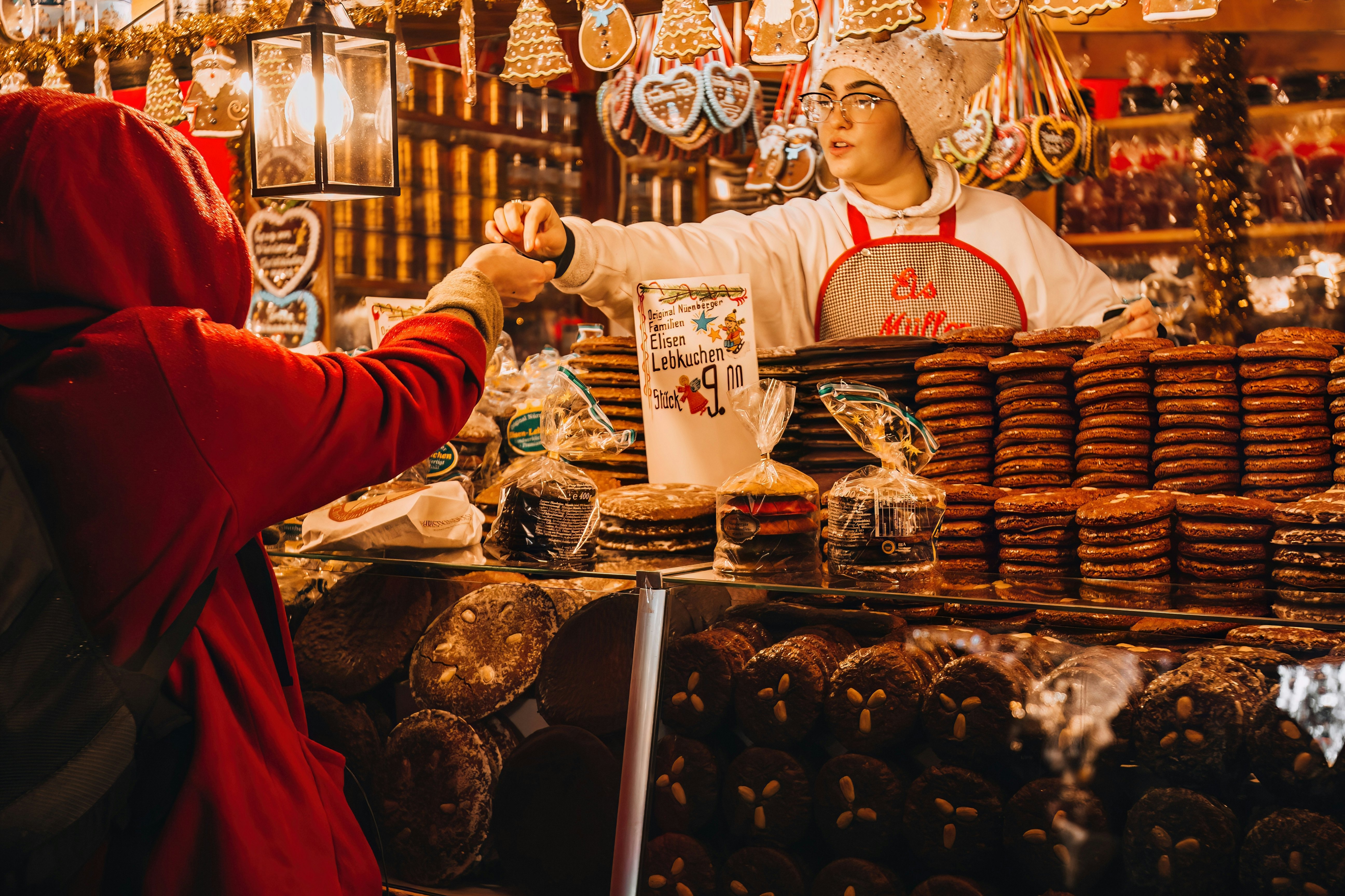 Nuremberg, Bavaria, Germany - December 01, 2023: A Customer and Gingerbread Seller at the 2023 Nuremberg Christkindlesmarkt (Christmas Market)