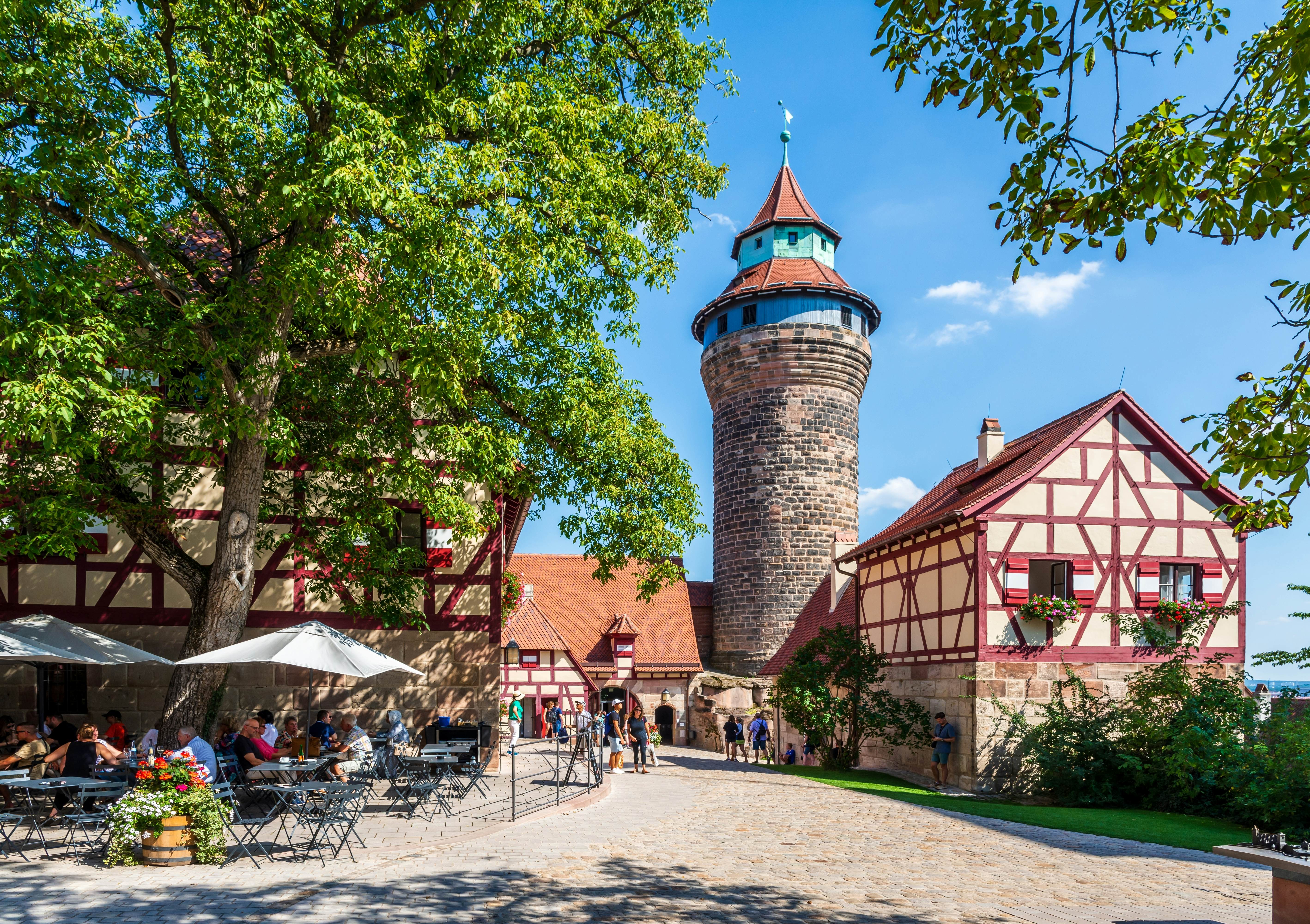 Nuremberg, Germany - August 23, 2023: Tourists enjoy the courtyard of the Kaiserburg medieval castle with the Tiefer Brunnen (well) in the Brunnenhaus half-timbered house and the Sinwellturm (keep)., License Type: media, Download Time: 2025-11-13T13:01:43.000Z, User: pinkjozie64, Editorial: true, purchase_order: 56530 - Guidebooks, job: Global Publishing WIP, client: Experience Germany 1, other: Jo-anne Riddell