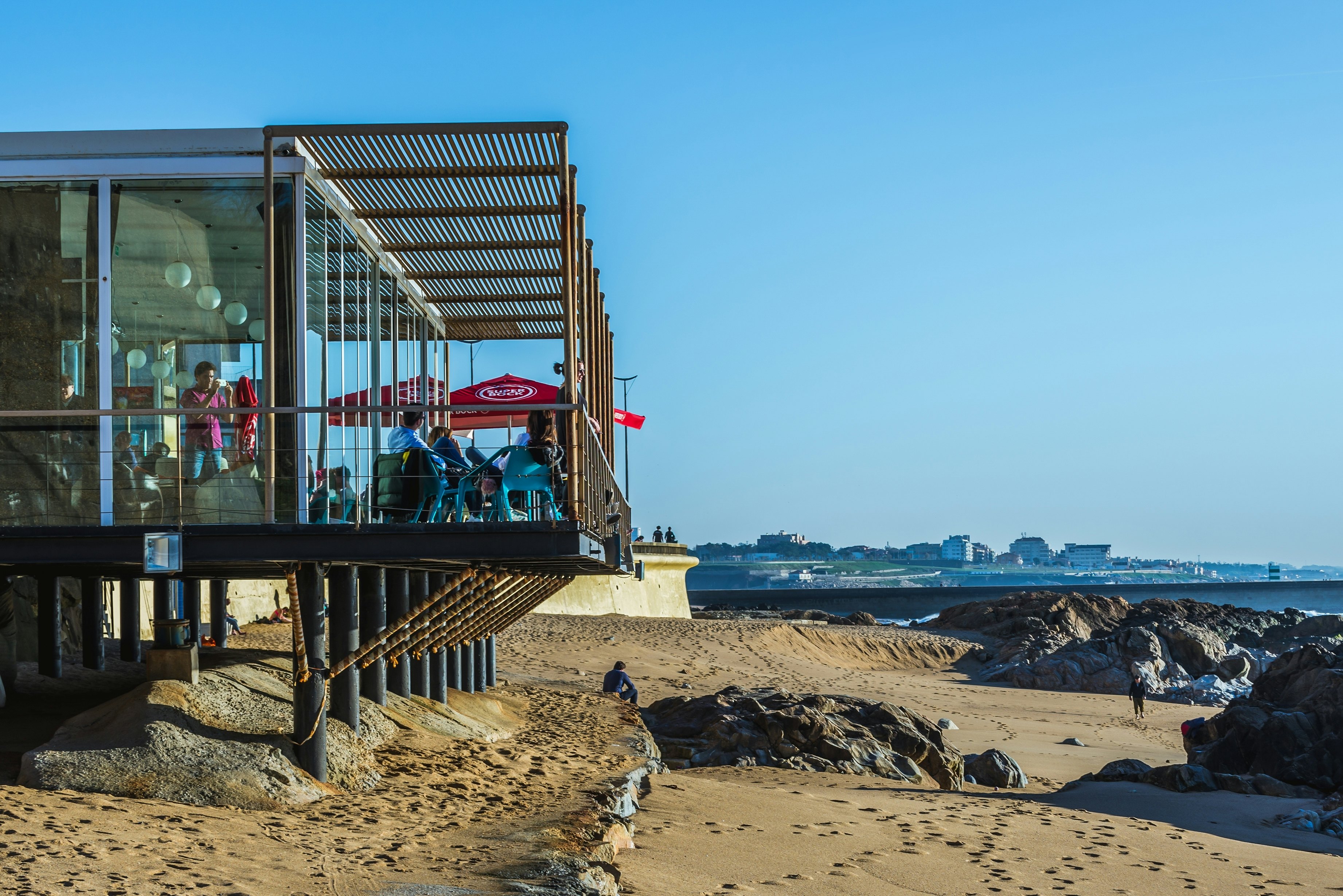 A beach bar with a balcony on stilts at the edge of the sand.