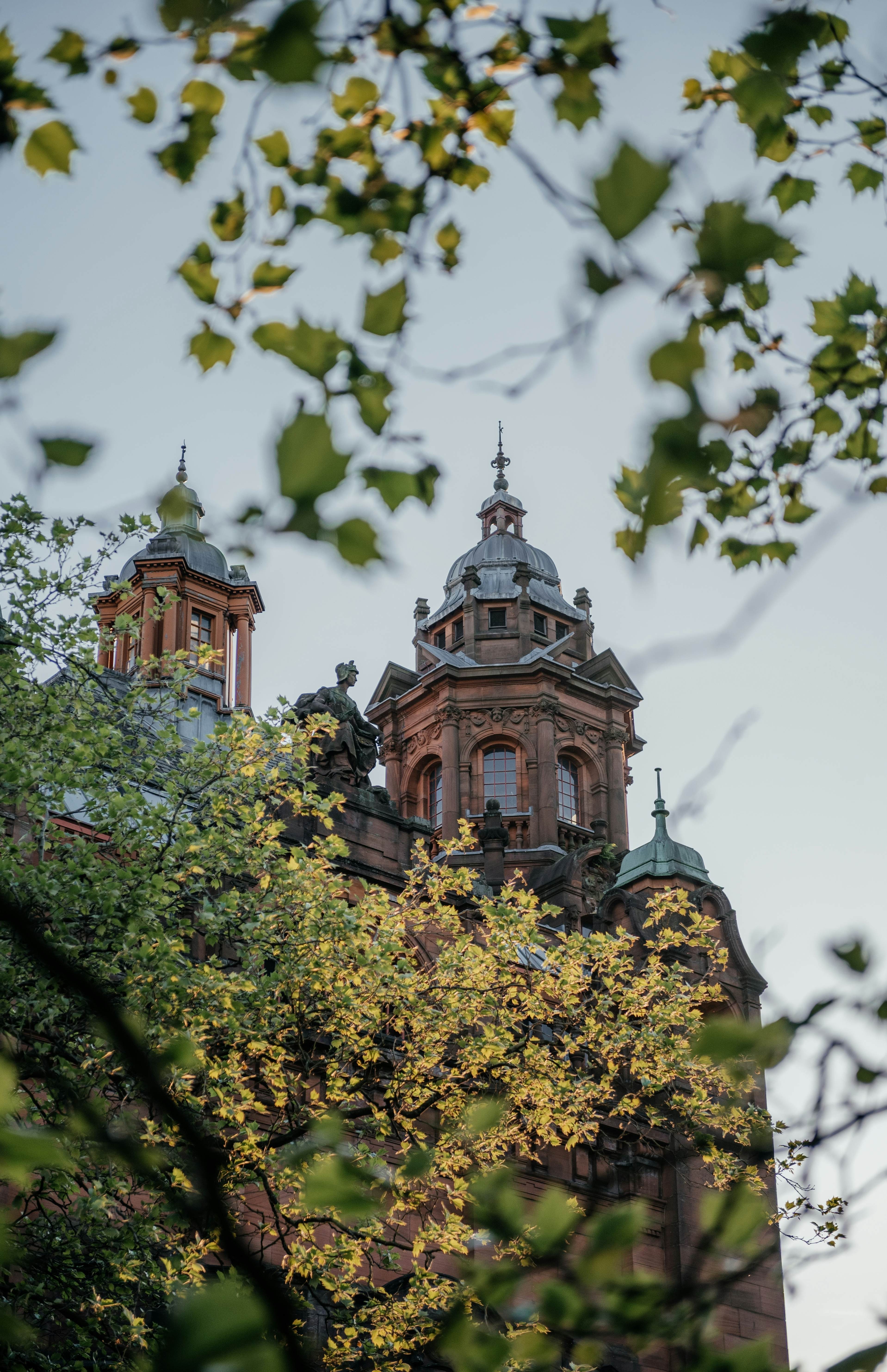 Turrets of a red-brick building in a city.