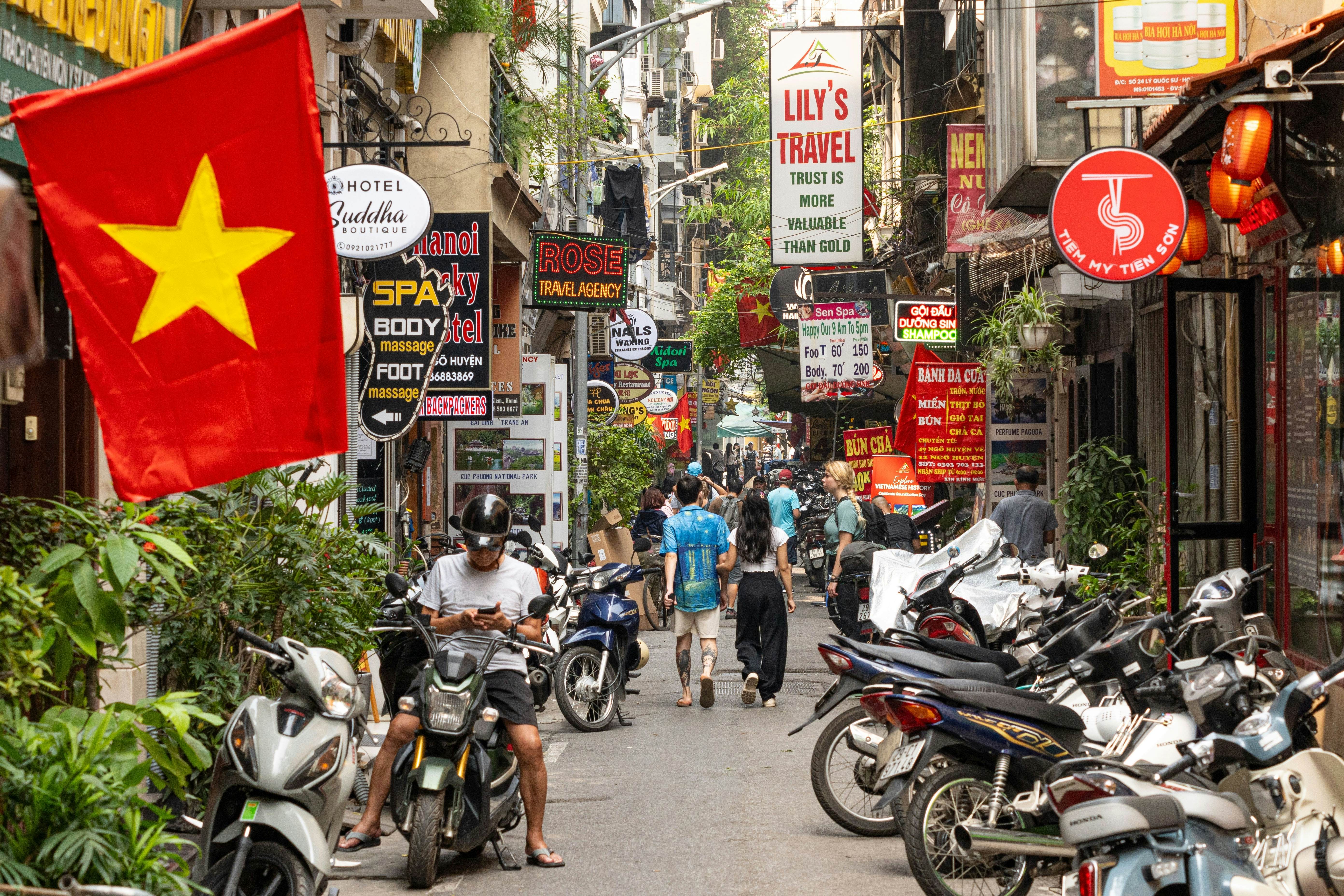 Hanoi Vietnam - April 24 2024: street life in Hanoi City at daytime with the red Hanoi flags and people on the street. The busy streets of in Hanoi with scooters, motorcycles, billboards and tourist. , License Type: media, Download Time: 2025-03-20T04:21:40.000Z, User: claramonitto, Editorial: true, purchase_order: 56530 - Guidebooks, job: Global Publishing-WIP, client: Vietnam 17, other: Clara Monitto