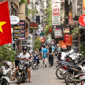 Hanoi Vietnam - April 24 2024: street life in Hanoi City at daytime with the red Hanoi flags and people on the street. The busy streets of in Hanoi with scooters, motorcycles, billboards and tourist. , License Type: media, Download Time: 2025-03-20T04:21:40.000Z, User: claramonitto, Editorial: true, purchase_order: 56530 - Guidebooks, job: Global Publishing-WIP, client: Vietnam 17, other: Clara Monitto