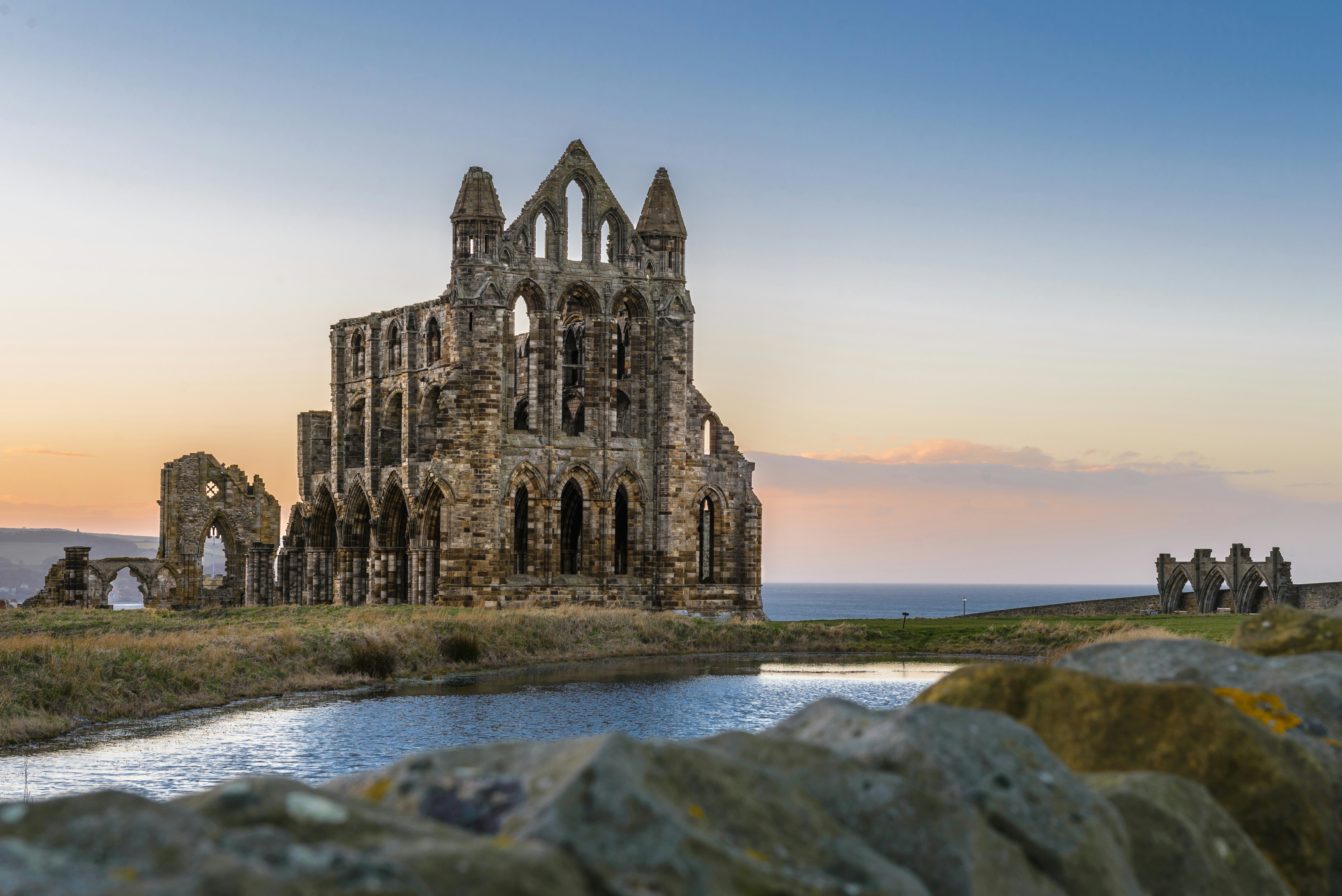 A view of the stone ruins of Whitby Abbey on the cliffs of Whitby, North Yorkshire, England at sunset.