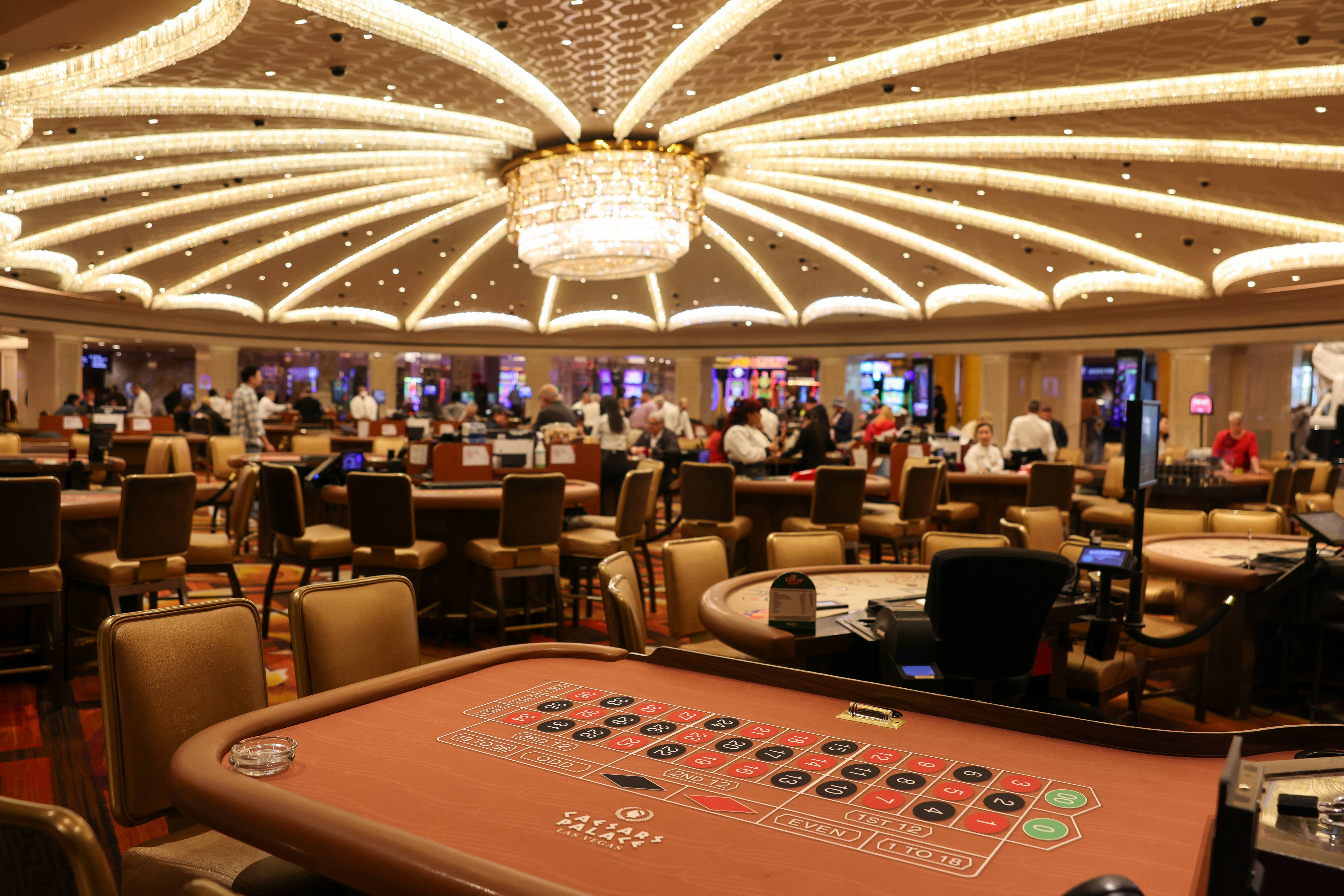 An empty table with numbers in black or red circles in a large room with other gambling tables.