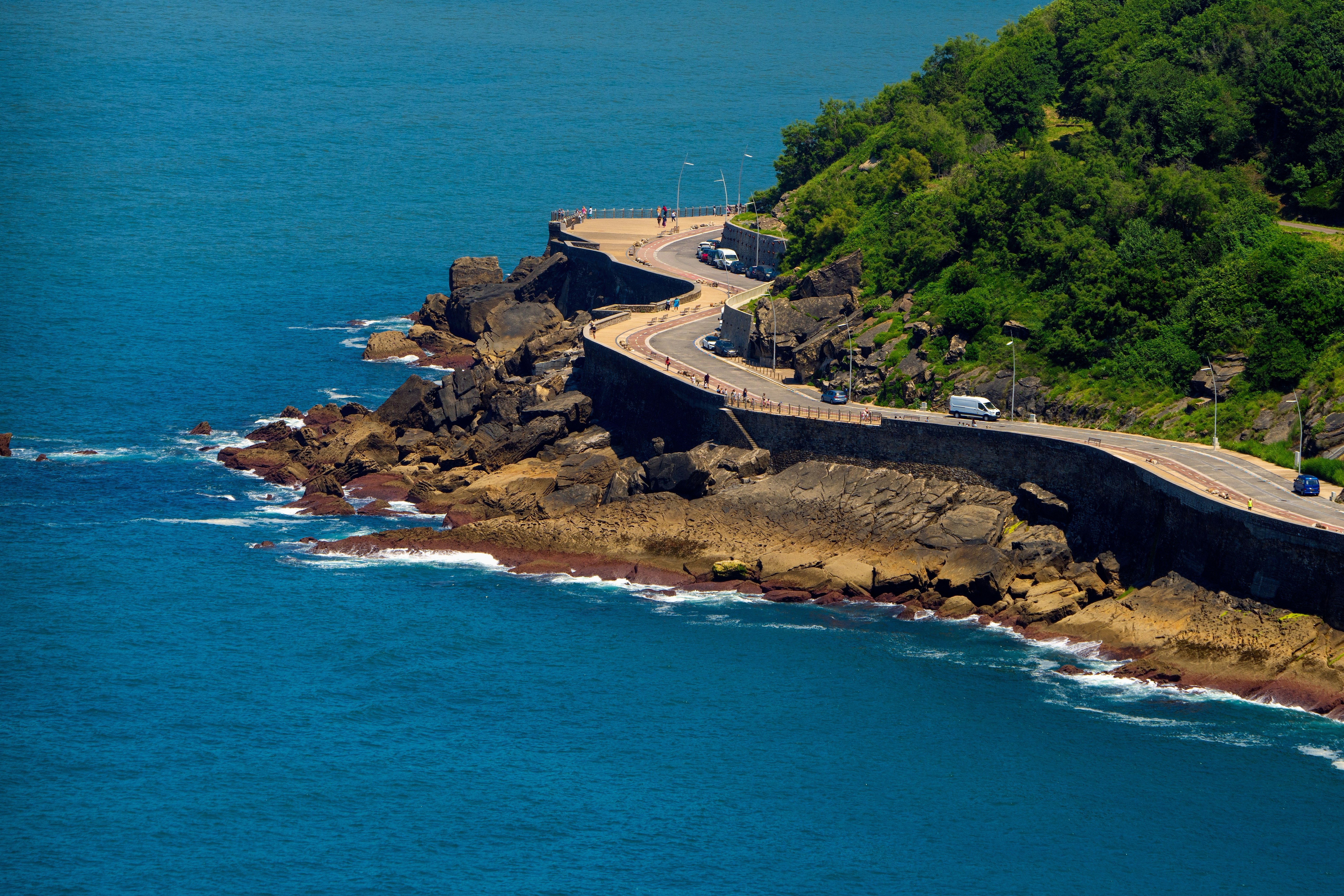 A wide view of a curvy road hugging the coast by the sea.