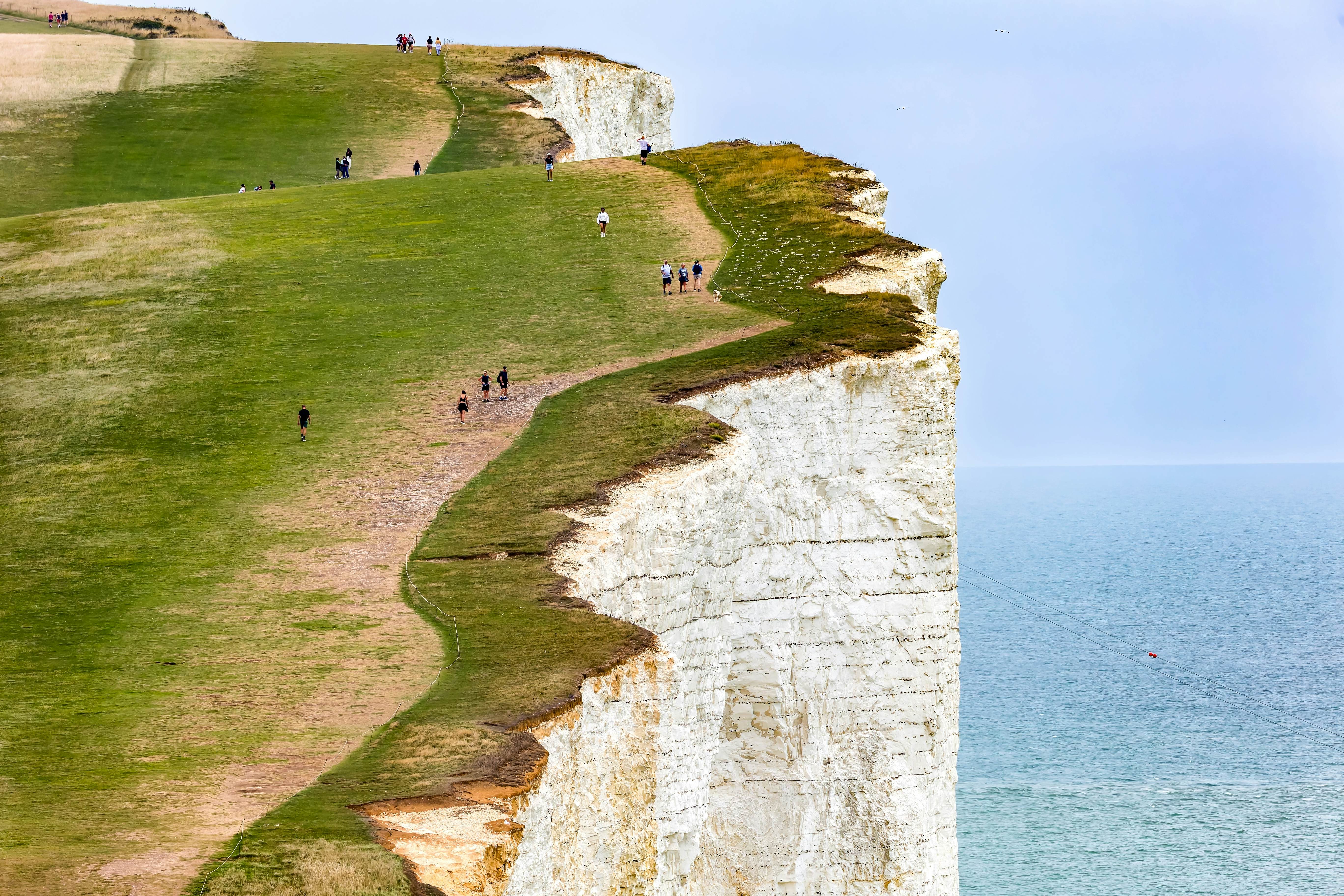 Beachy Head, England - 08-08-2025: Scenic view of the Sussex coastline with walkers on the famous cliffs of Beachy Head., License Type: media, Download Time: 2025-12-17T15:47:36.000Z, User: katelyn.perry_lonelyplanet, Editorial: true, purchase_order: 65050 - Digital Destinations and Articles, job: wip, client: wip, other: Katelyn Perry