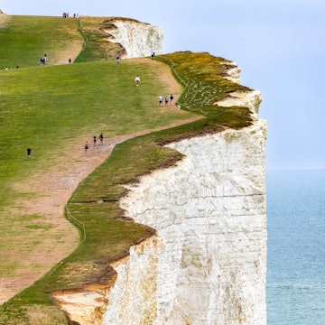 Beachy Head, England - 08-08-2025: Scenic view of the Sussex coastline with walkers on the famous cliffs of Beachy Head., License Type: media, Download Time: 2025-12-17T15:47:36.000Z, User: katelyn.perry_lonelyplanet, Editorial: true, purchase_order: 65050 - Digital Destinations and Articles, job: wip, client: wip, other: Katelyn Perry
