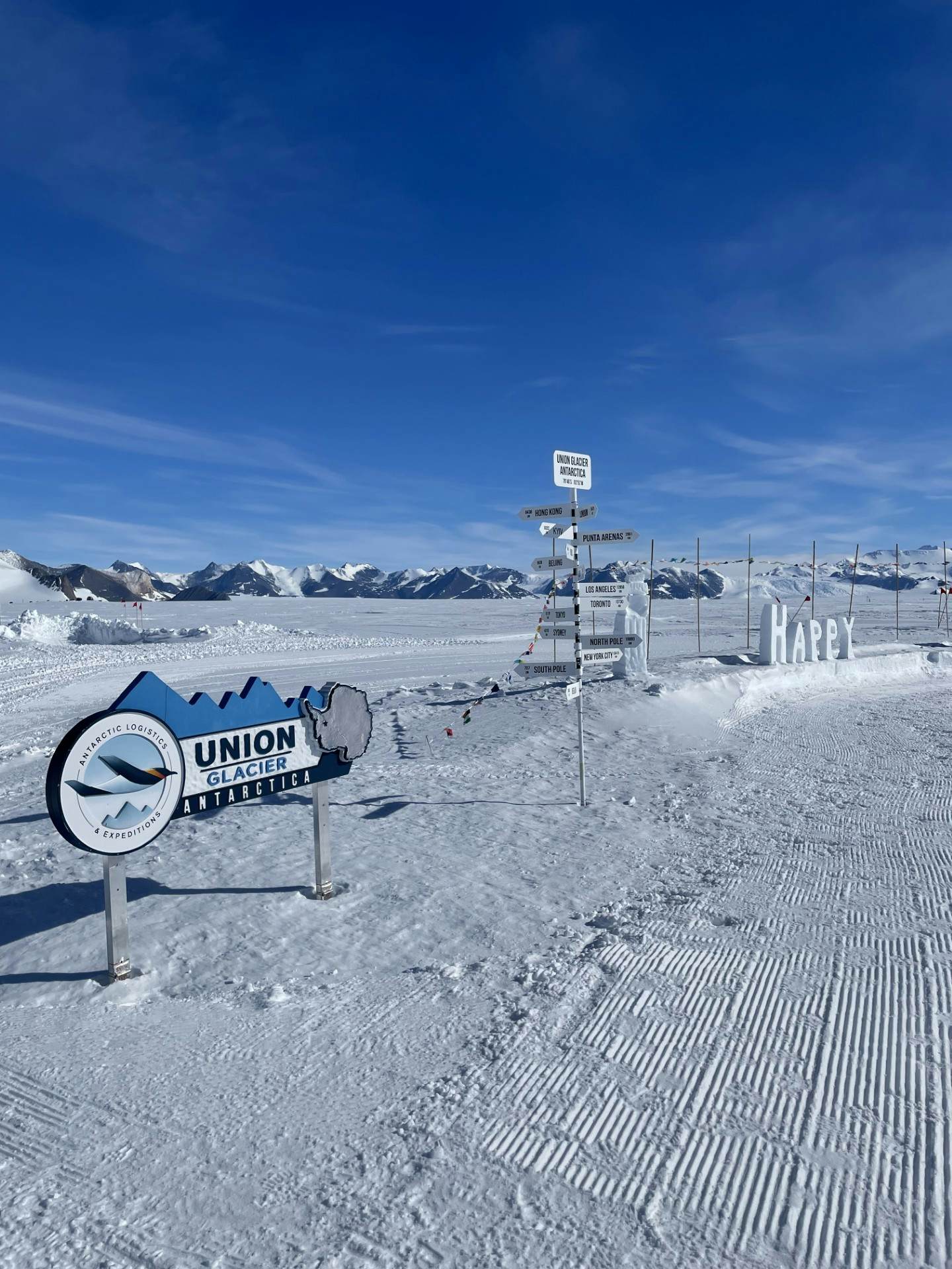 A series of signs in a snowy landscape pointing directions to different places on Earth