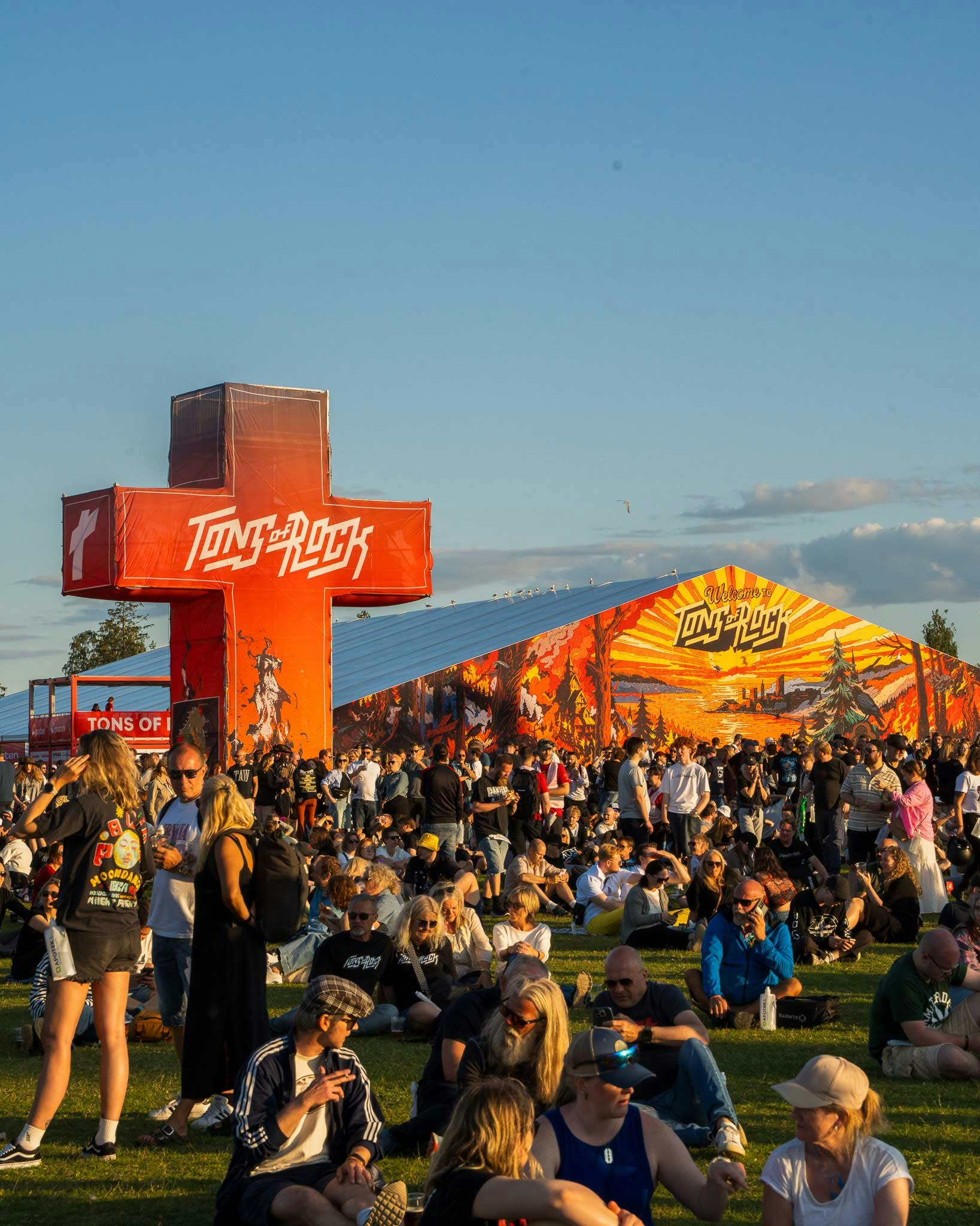 People sitting on grass taking a break in the afternoon sun at Tons of Rock