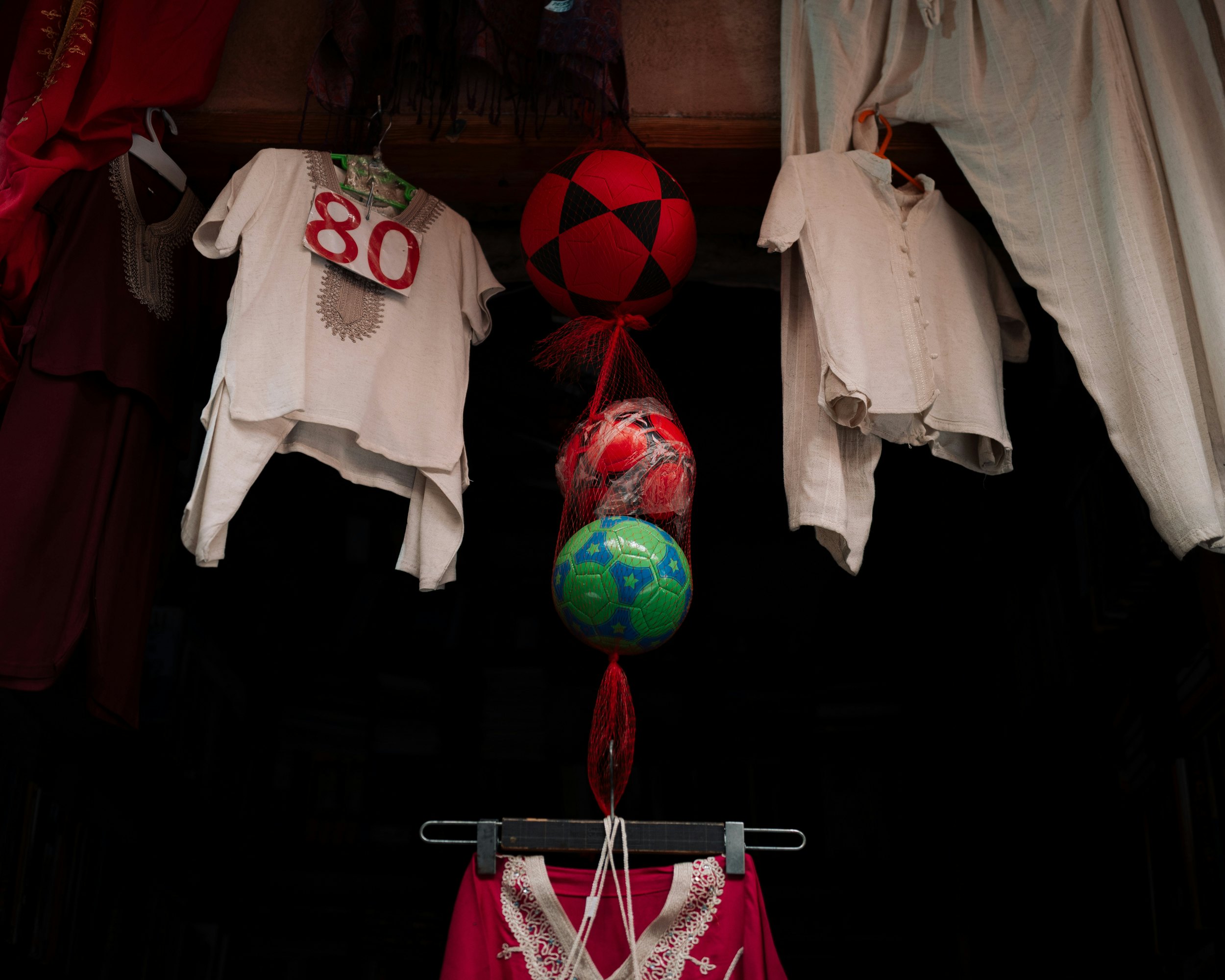 Clothing items and soccer balls for sale at a Moroccan street market in the Casablanca medina.