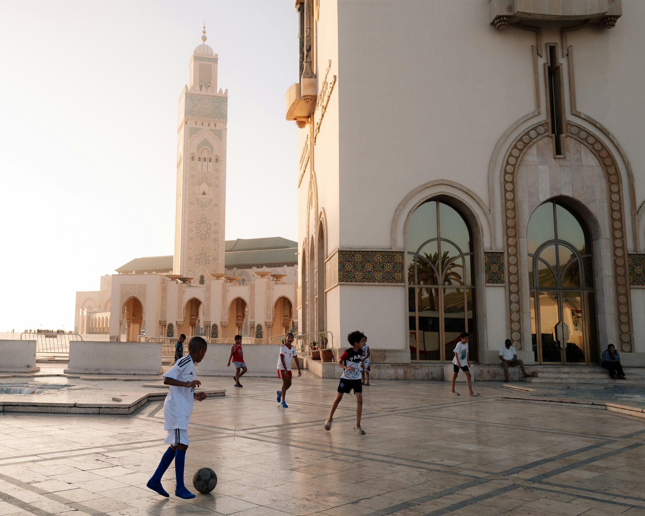 Children playing soccer in front of the Hassan II Mosque in Casablanca, Morocco.