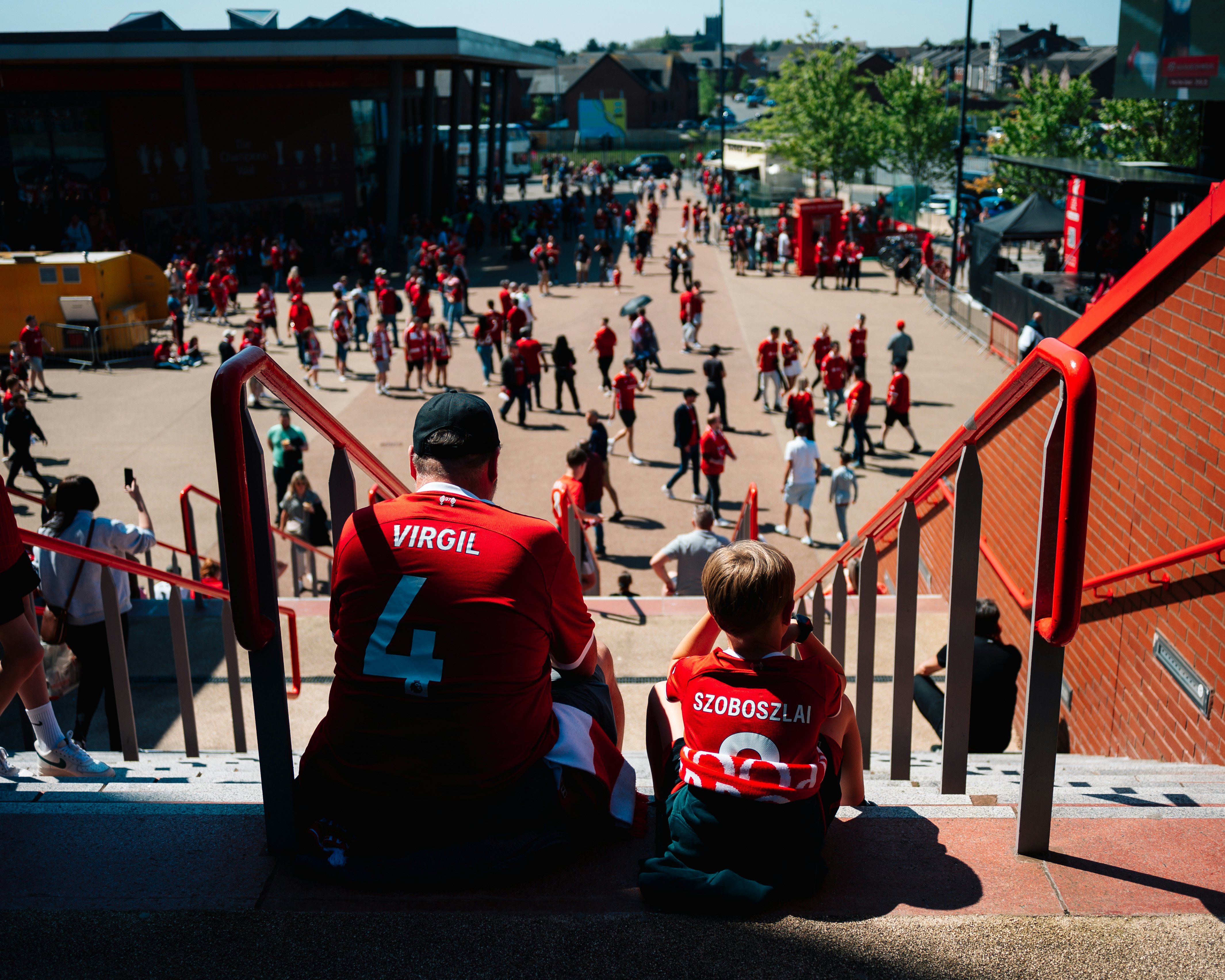 A father and son wait for doors to open at Liverpool's Anfield Stadium in 2024.