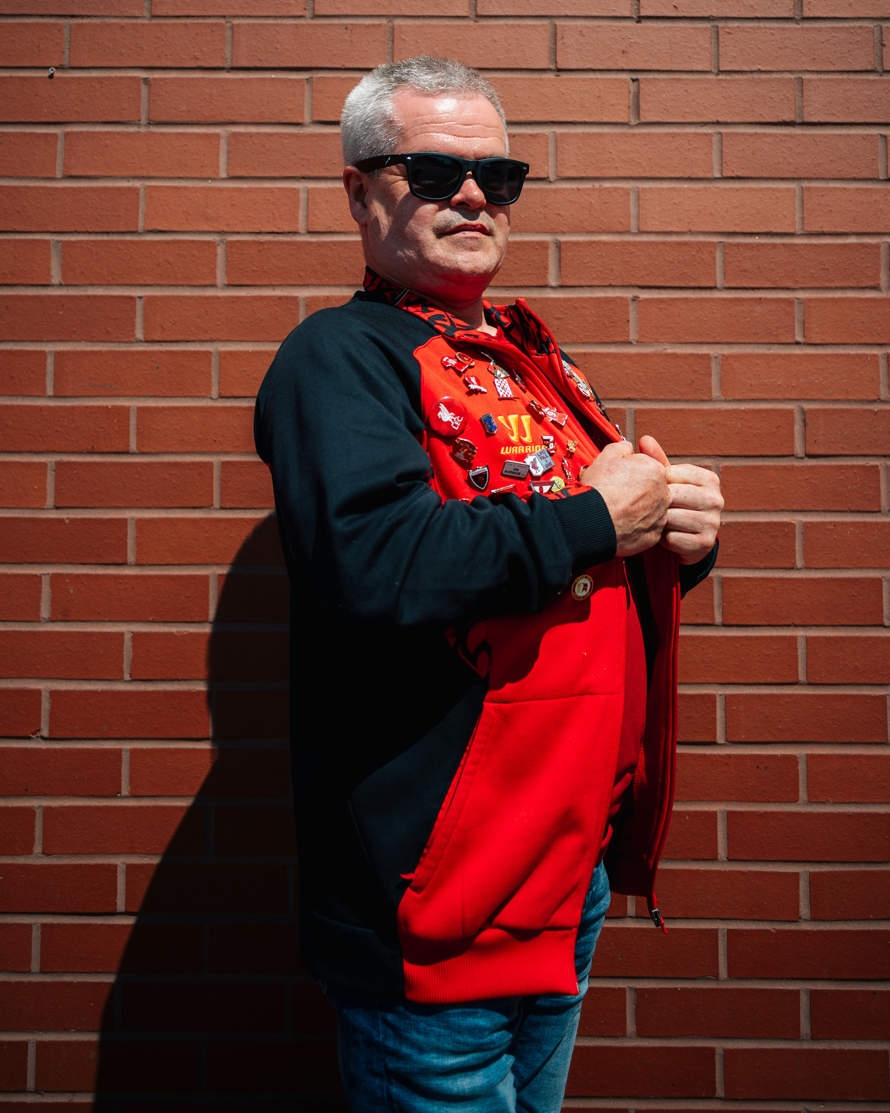 A Liverpool soccer fan poses outside Anfield Stadium in Liverpool, UK.