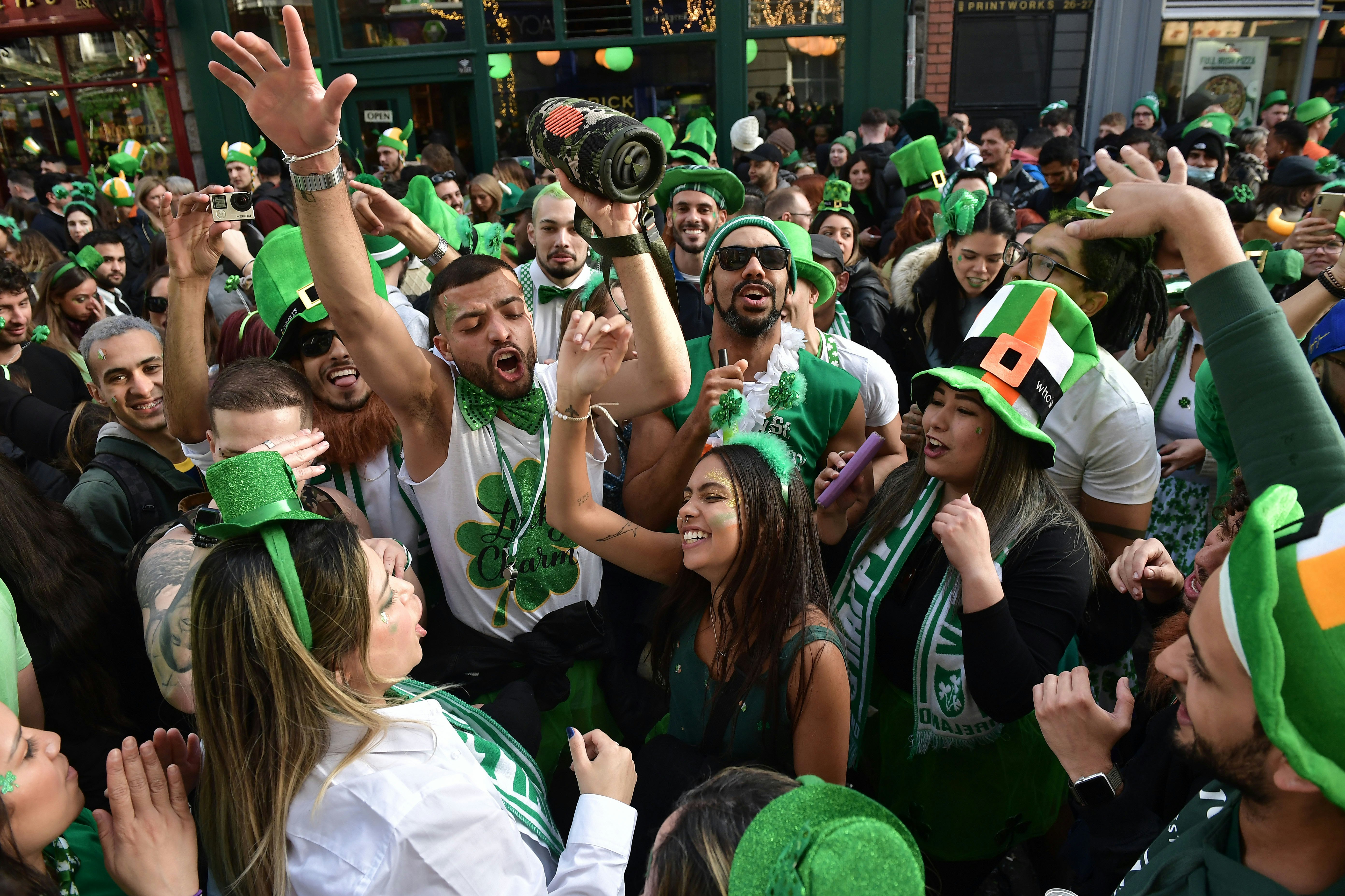 A crowd celebrating in green hats and other green clothing, some with shamrocks
