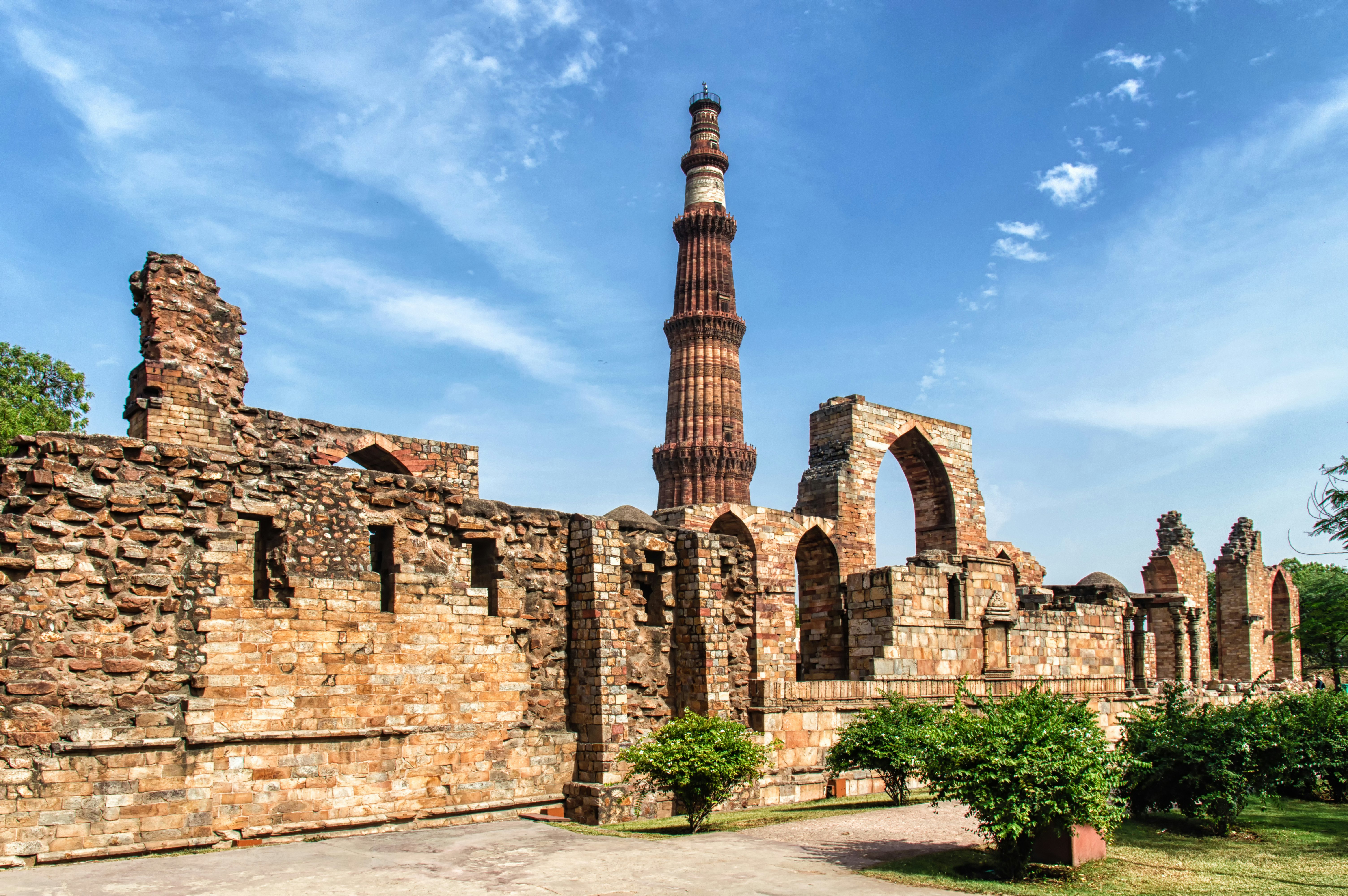 A tall ancient minaret rises above brick ruins.