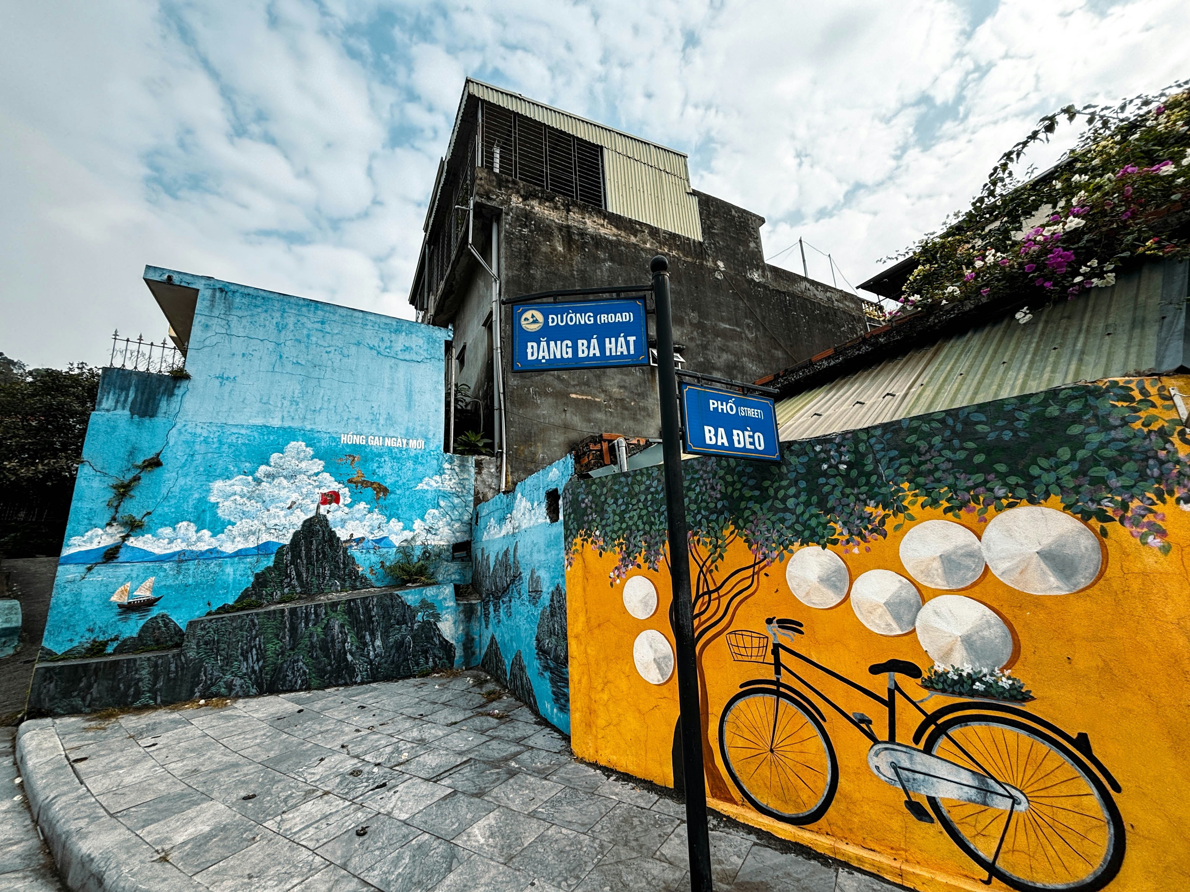 Murals of a cloudy Halong Bay and a bicycle topped by Vietnamese hats in Halong City, Vietnam.
