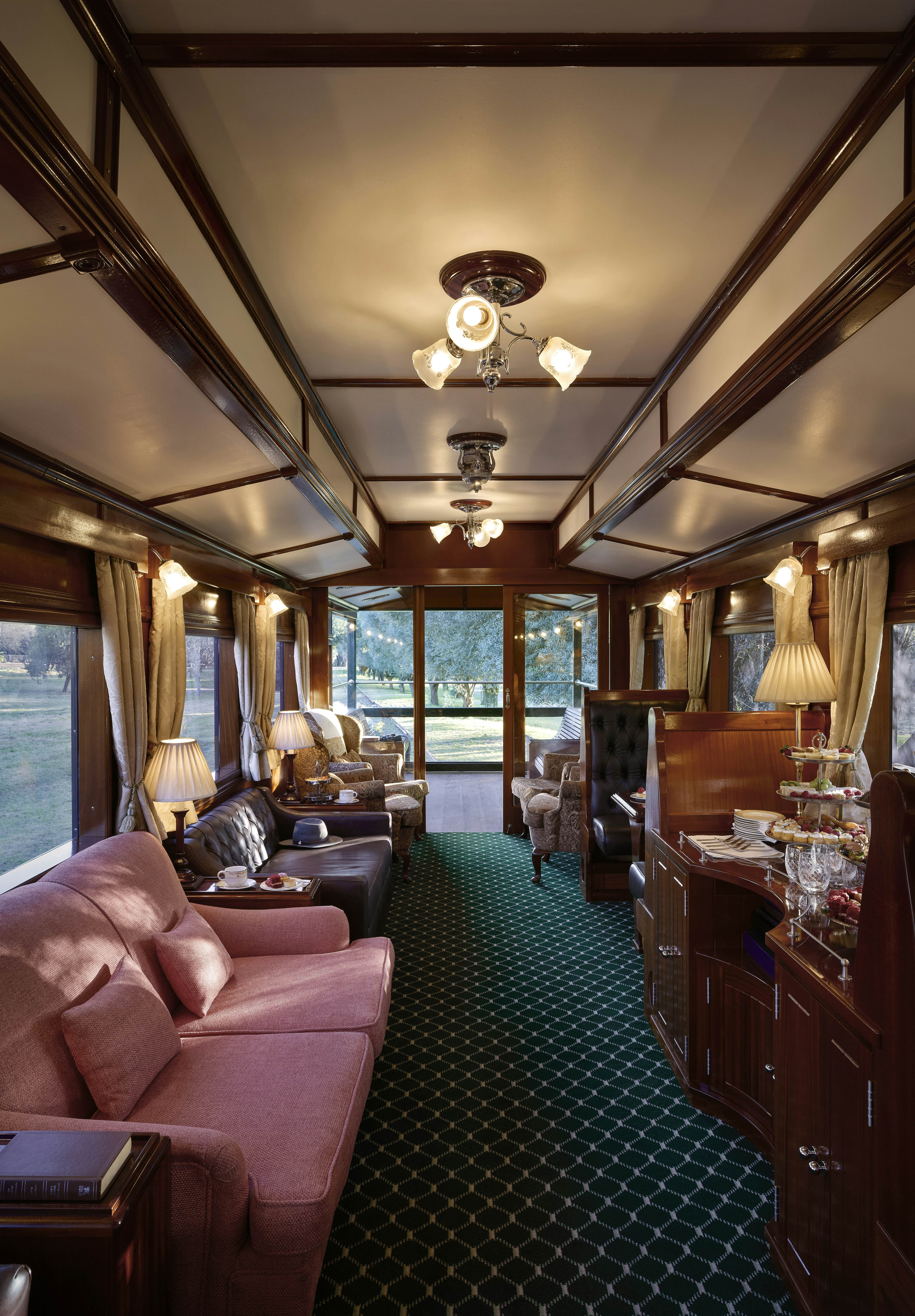 A seating area in a train carriage, with large armchairs and smaller seats at tables.