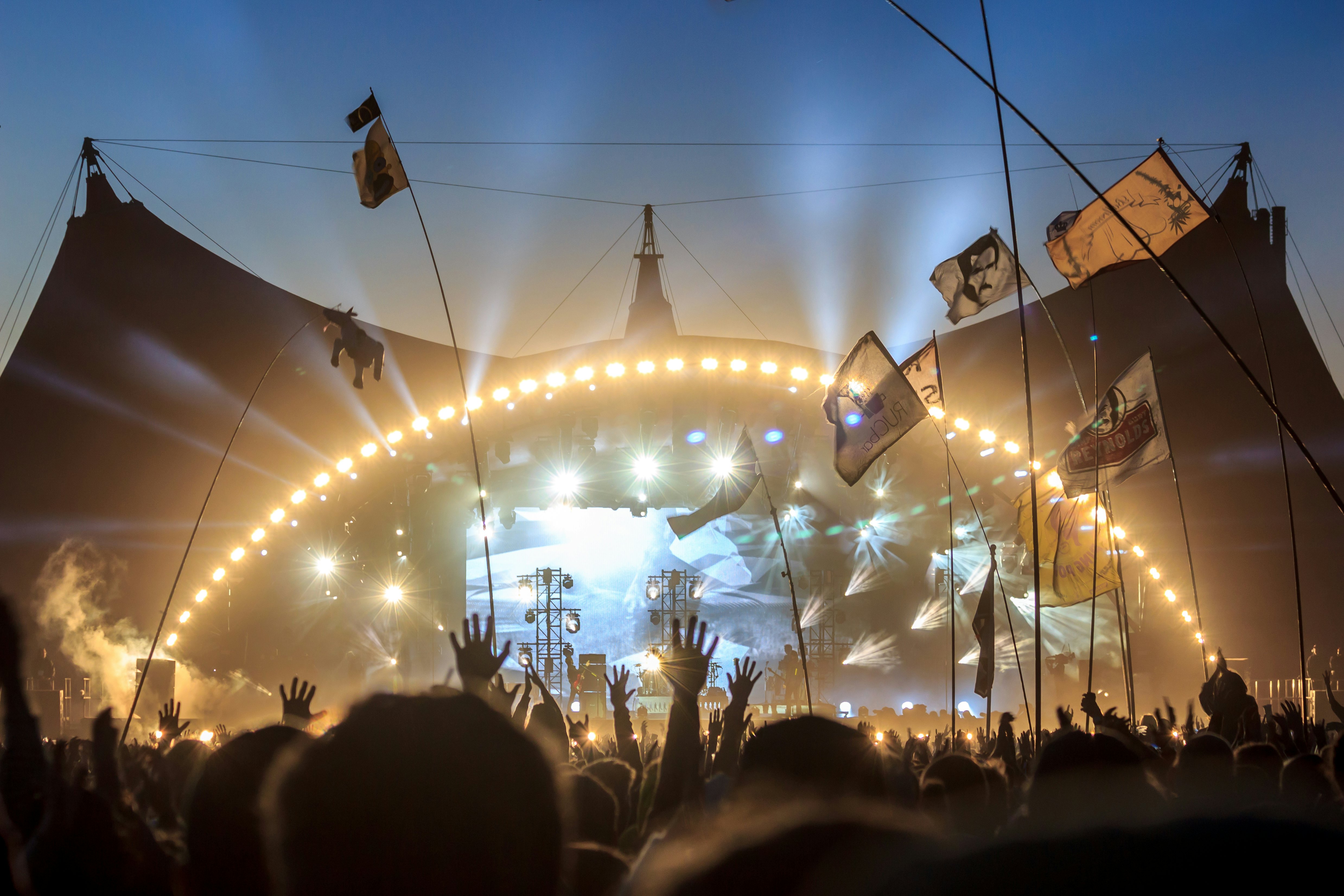 Audience with flags and banners, raising their hands in front of the stage at Roskilde Festival. Roskilde Festival is one of the largest music festivals in Europe.