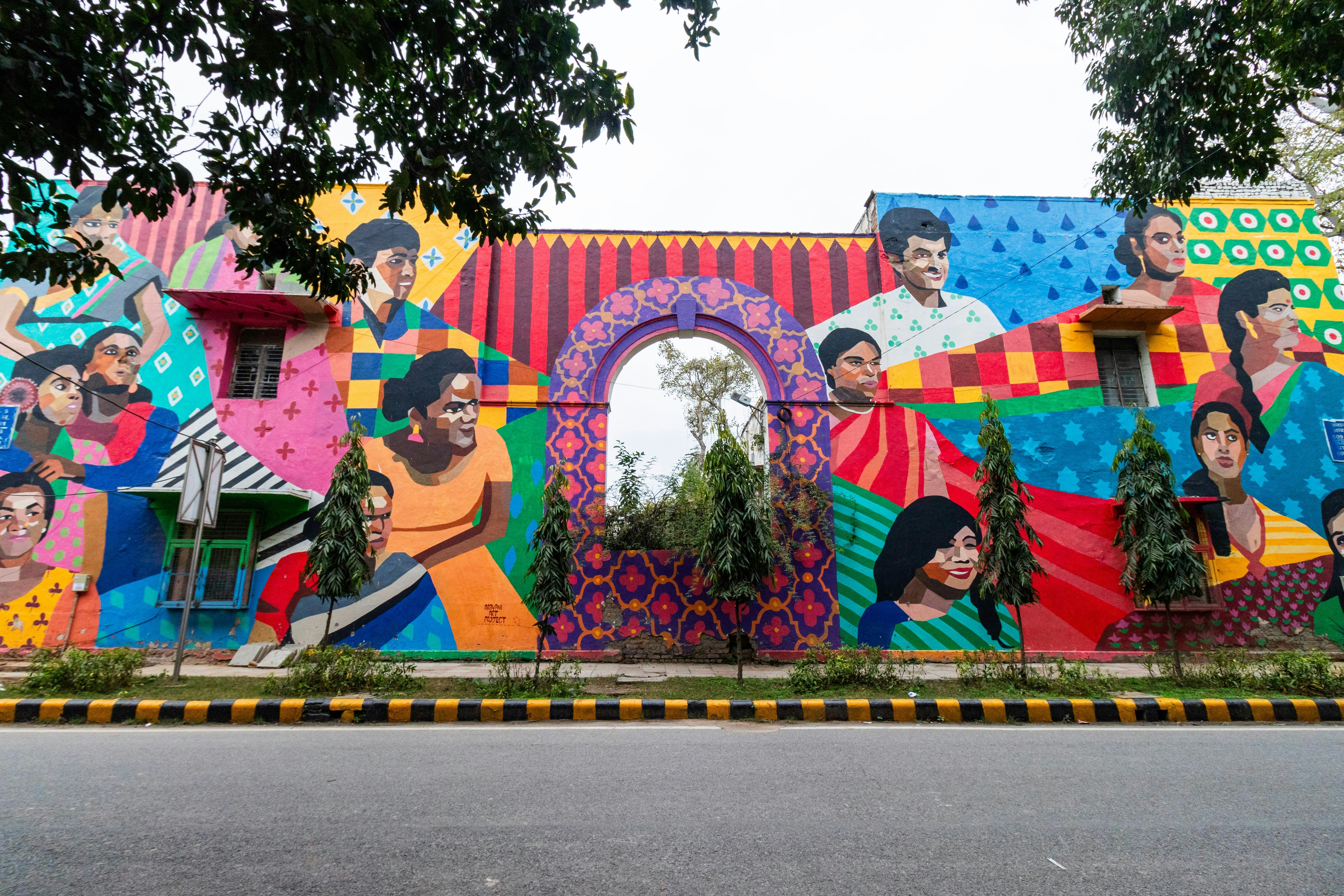 A vast wall painted in bright colors with murals of men an women.