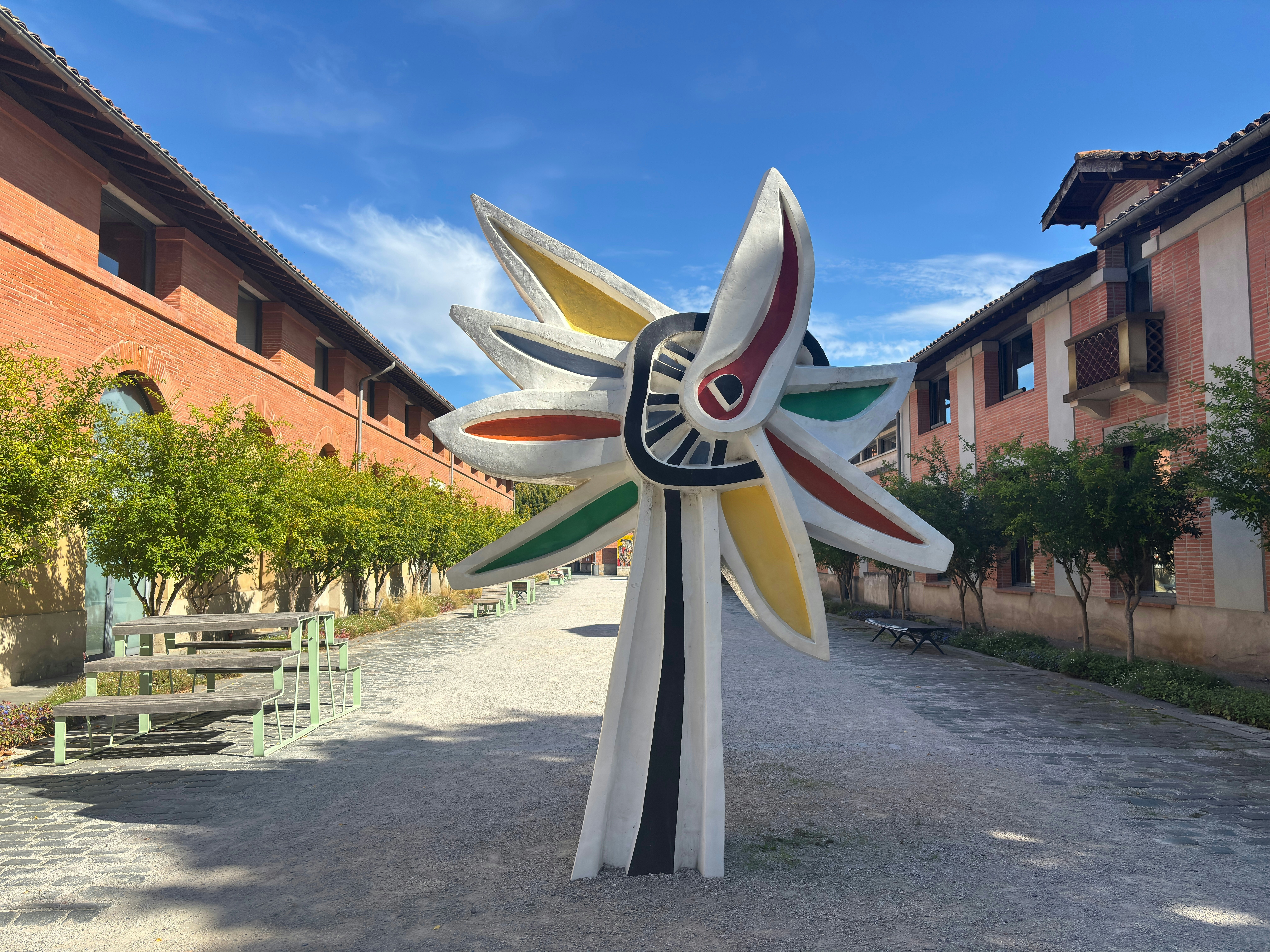 A sculpture in a courtyard with redbrick buildings on either side.