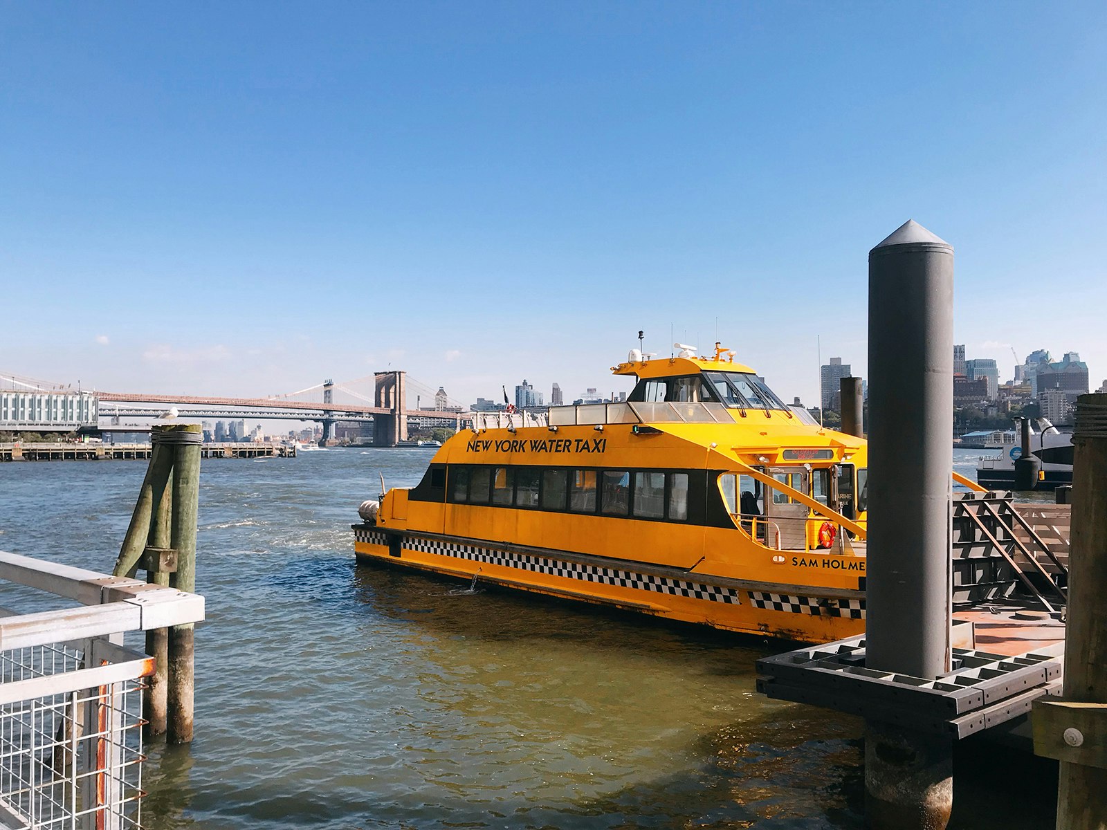 the bright yellow NY Water Taxi docks in Brooklyn, with a bridge in the background