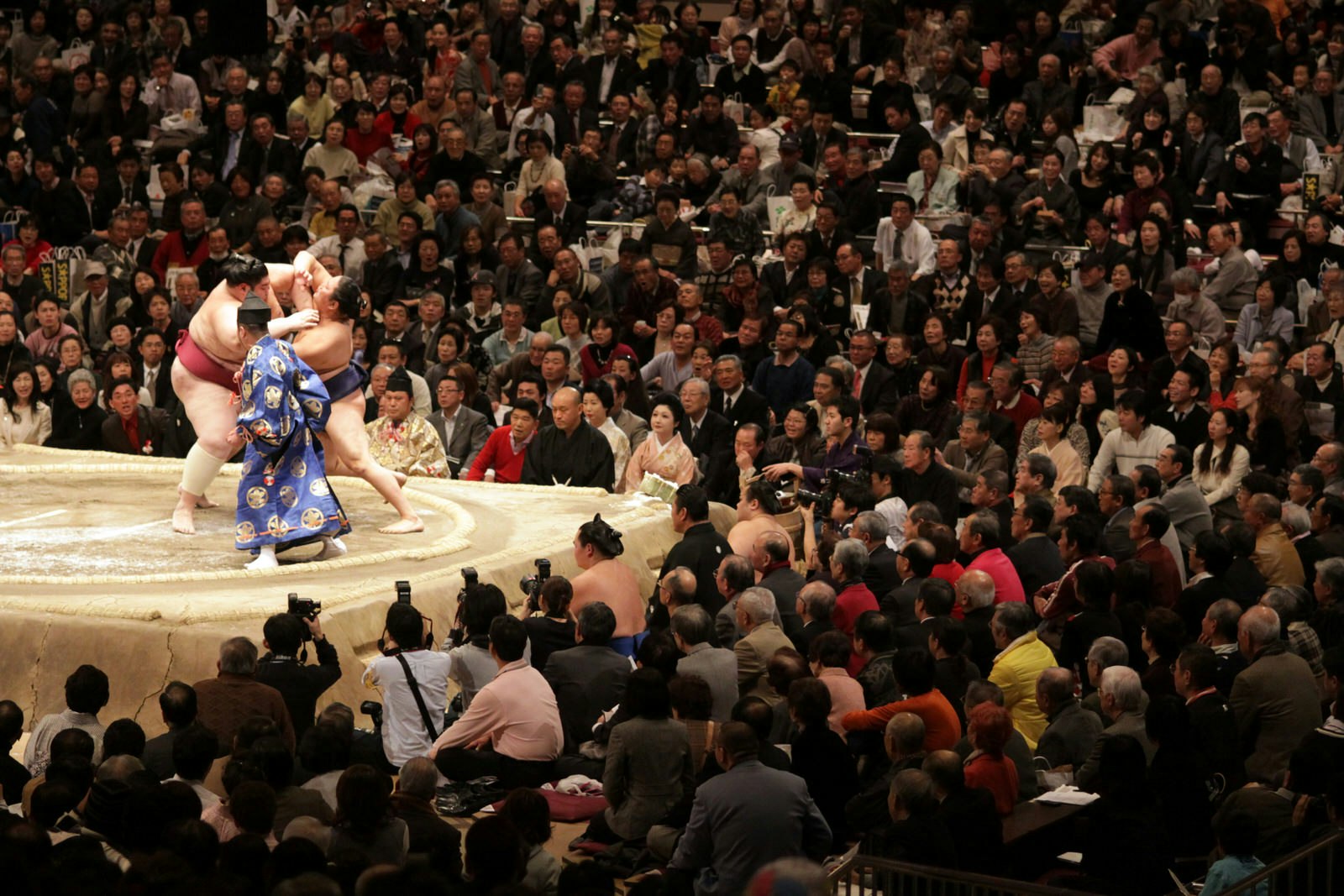 View of the large crowd around the ring as two wrestlers fight