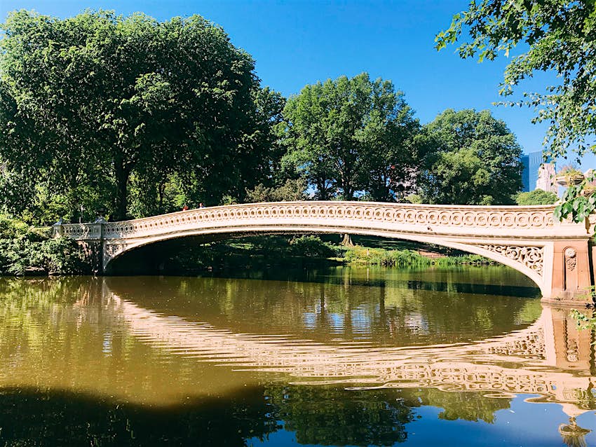 Bow Bridge stretches across Central Park Lake on a summer day; ways to enjoy New York City in the summer