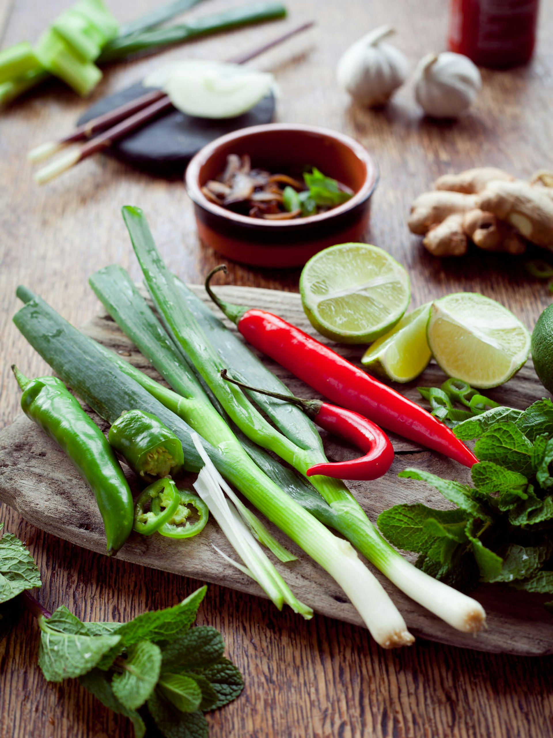 A board with spring onion, ginger, chilli, coriander, garlic and lime arranged ready for cooking © Joanna Tkaczuk / Shutterstock
