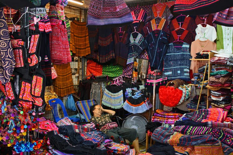  en klærleverandør har et øyeblikk av pusterom På Chatuchak Weekend Market, Bangkok. Bilde av istolethetv CC BY 2.0 