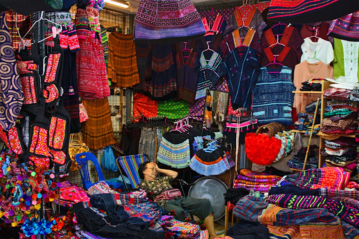 en klädförsäljare har ett ögonblick av paus på Chatuchak Weekend Market, Bangkok. Bild av Istolethetv CC BY 2.0