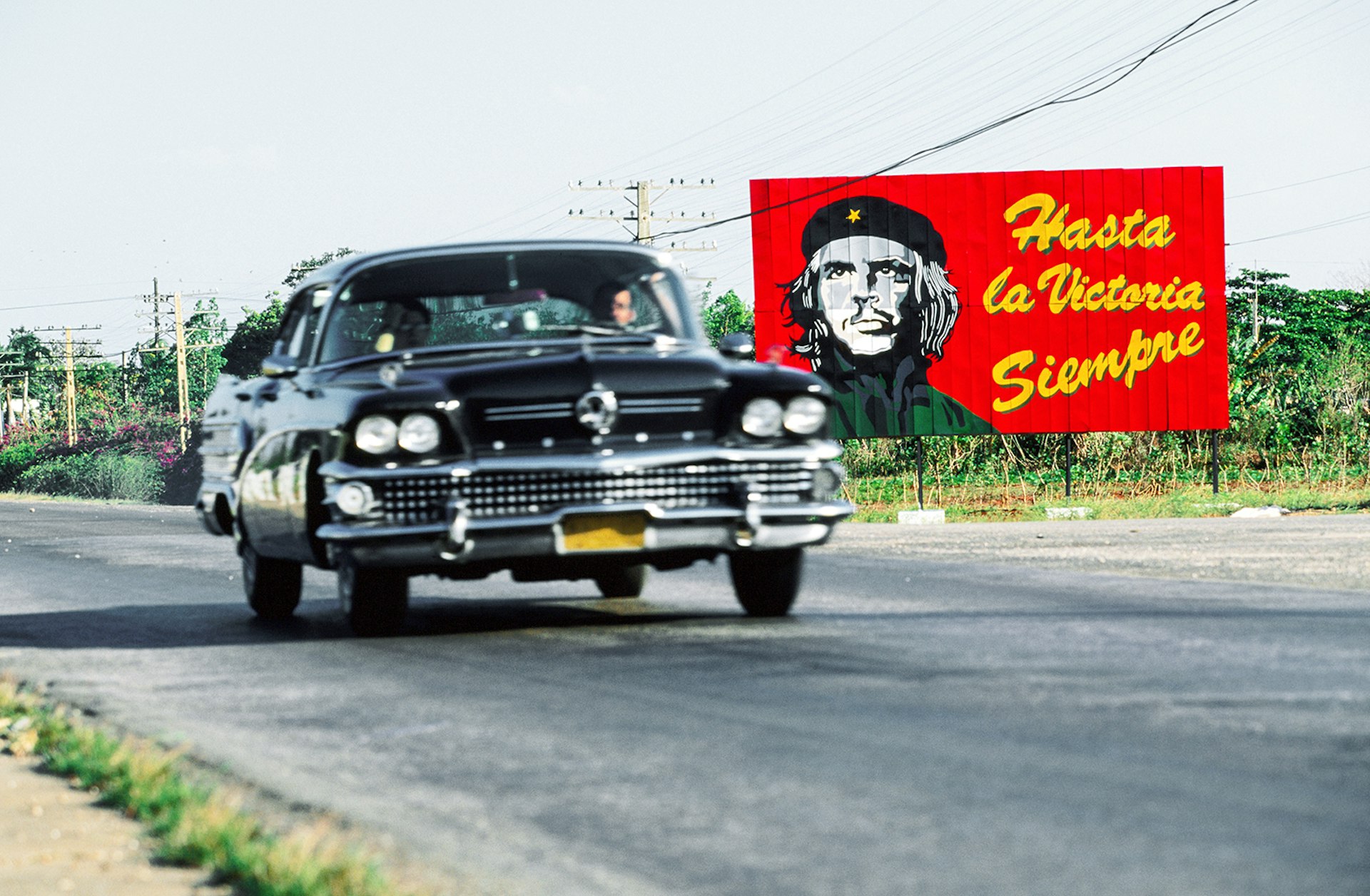 Features - 1958 Buick Century passing Che Guevara billboard.
