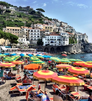 Beachgoers relaxing under umbrellas on the Amalfi Coast. Image by Mark Waind / EyeEm / Getty