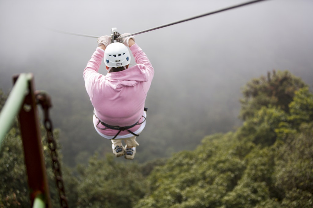 Features - Woman sliding down zipline in rainforets, rear view, close-up