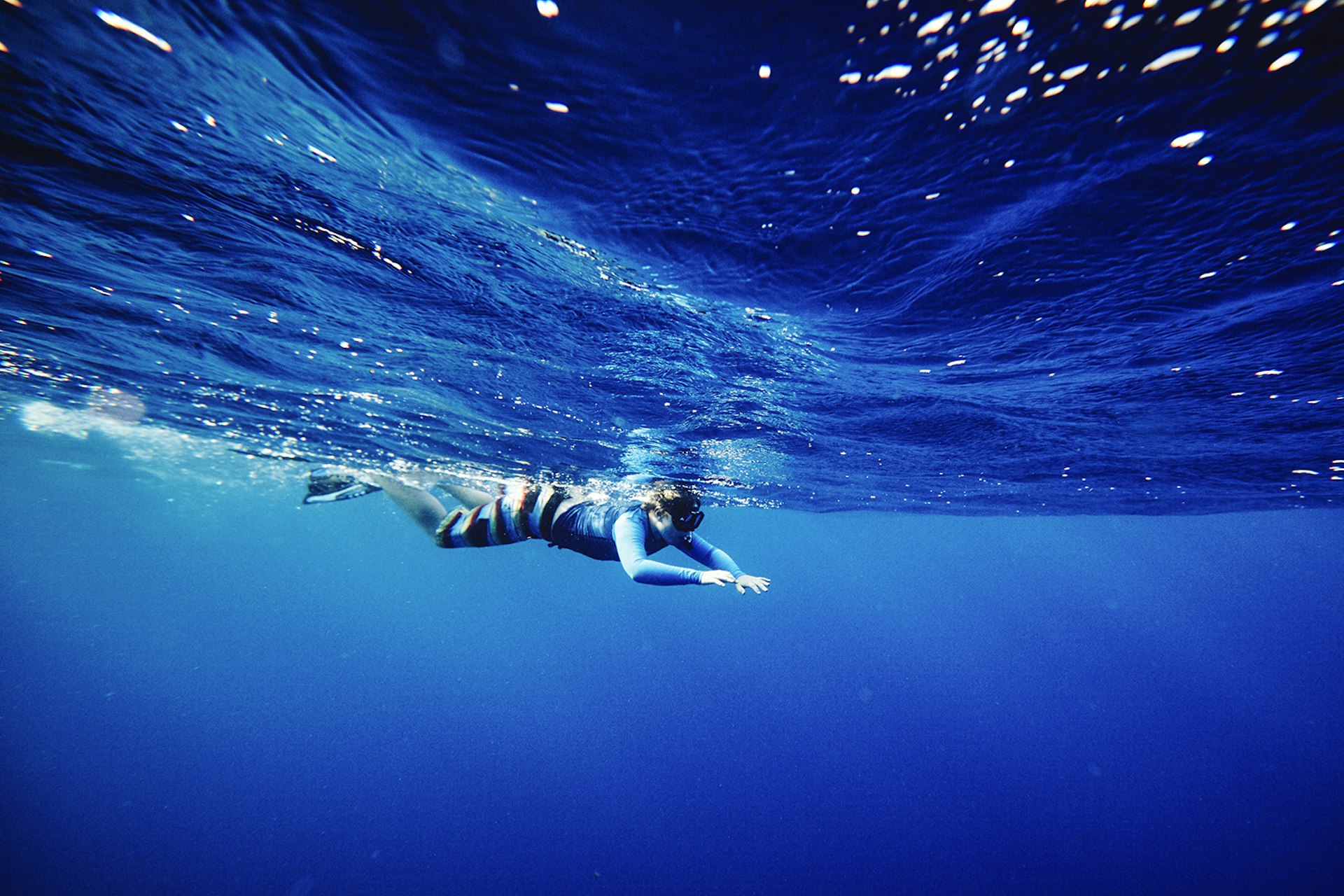 Features - Young boy snorkeling in open water underwater view