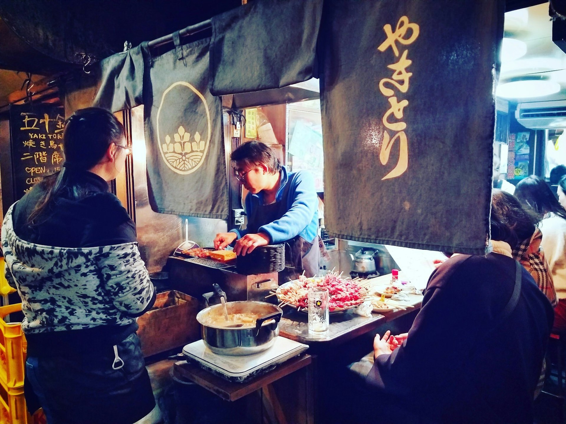 A man serves grilled chicken skewers at a tiny restaurant open onto the street in the Golden Gai area of Tokyo © Khaikholun Vaiphei / Shutterstock