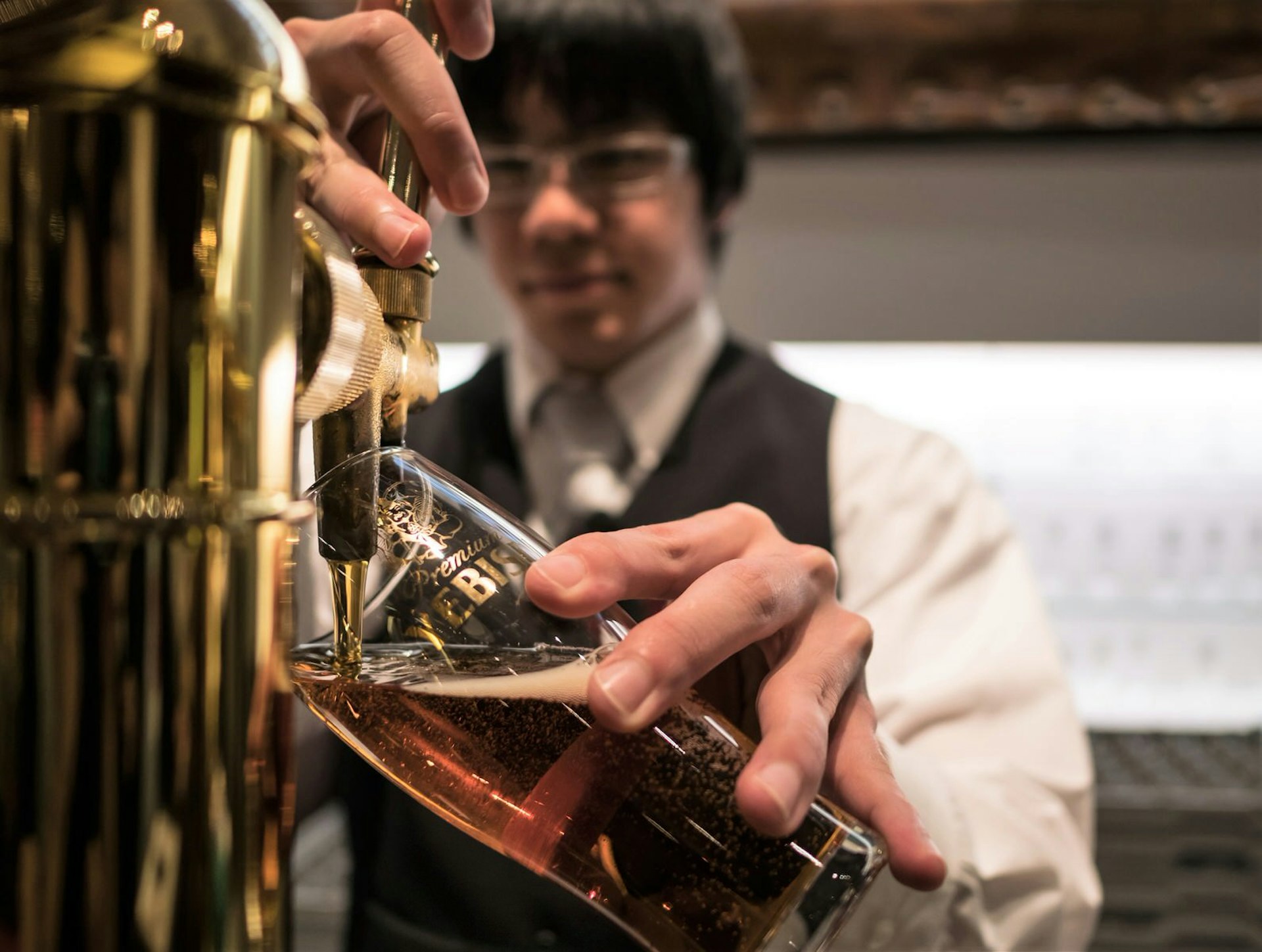 Close up of a glass with the Yebisu logo as beer is being poured into it at Beer Museum Yebisu in Tokyo © karanik yimpat / Shutterstock