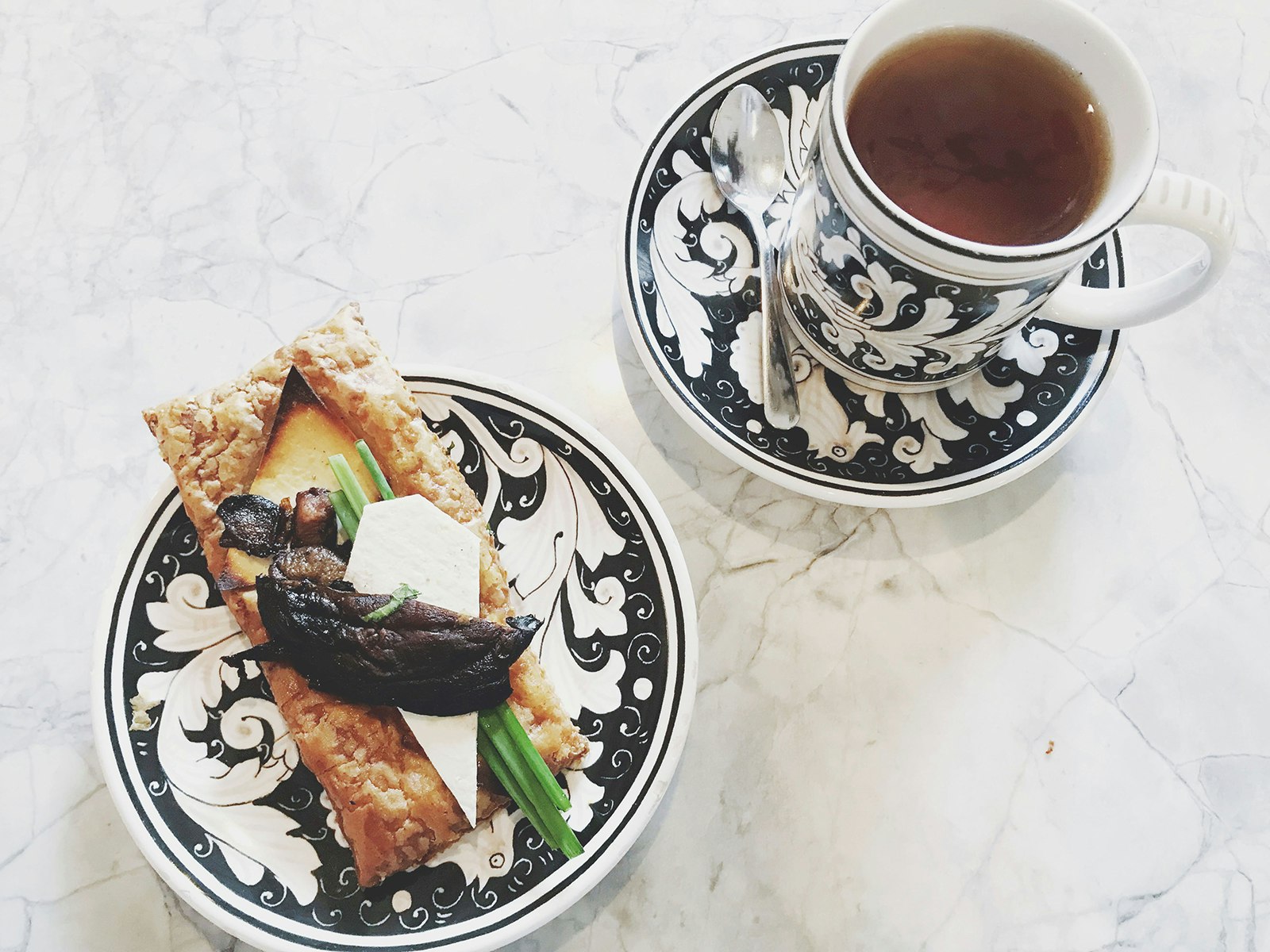 coffee in a cup and saucer and pastry on a matching plate 