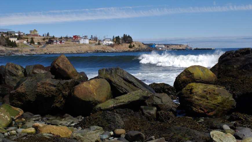 Wave rolling in to the beach, Witless Bay, Newfoundland. View from almost ground level looking across the beach to the water. Part of the town of Witless Bay can be seen in the background.