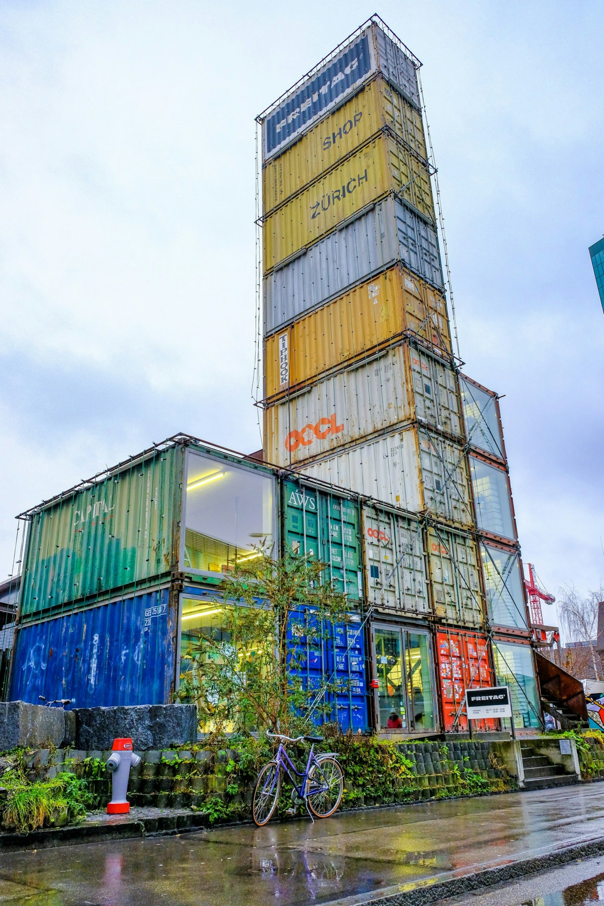 Made entirely of shipping containers, the Frietag shop in Zürich, Switzerland rises up against a grey sky © chayakorn.t / Shutterstock