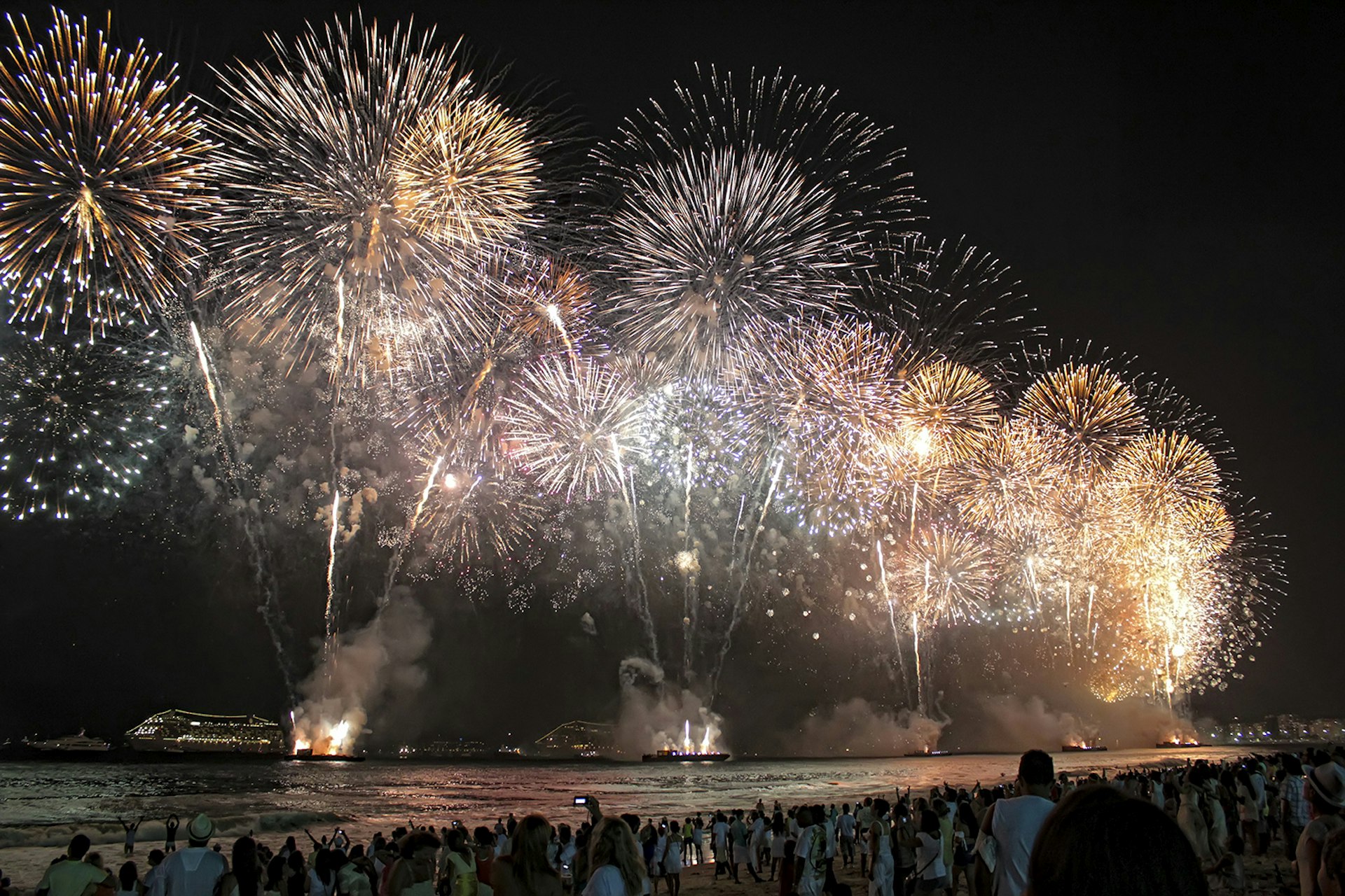 A crowd watches a large fireworks show from Copacabana