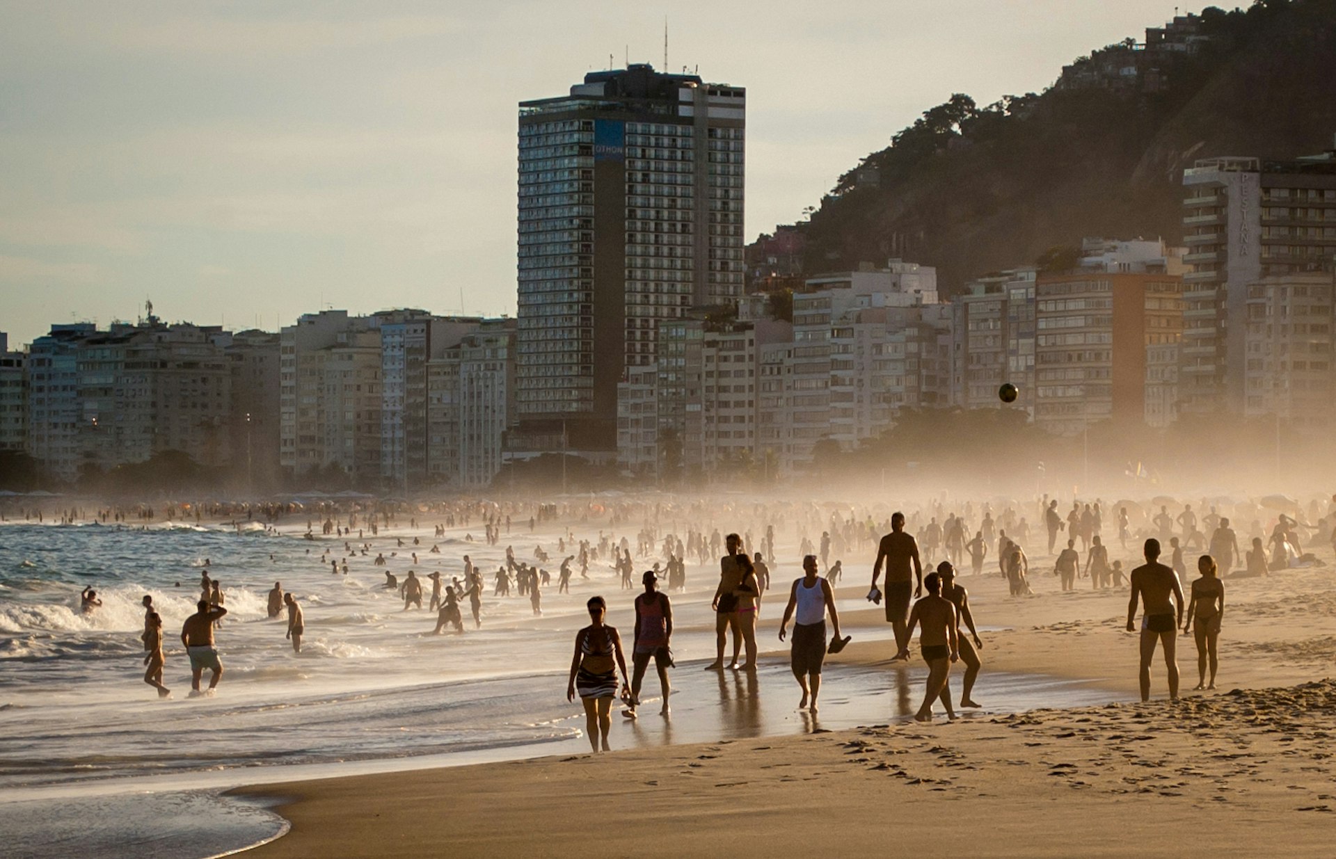 People walk on the beach at Copacabana in Rio at golden hour © Tom Le Mesurier / Lonely Planet