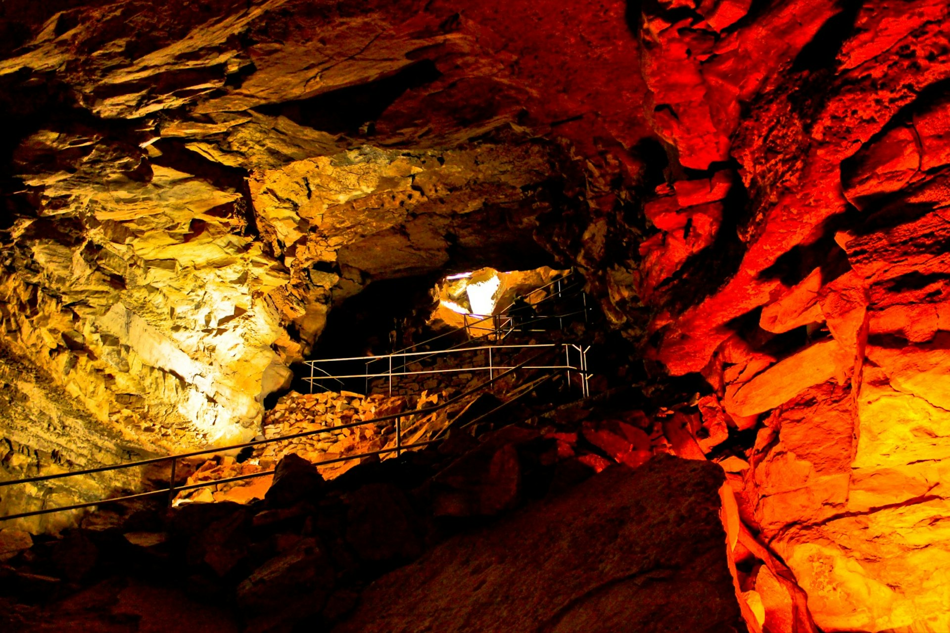 Railings and lights lead the way through a dark cave passage in Kentucky. Mammoth Cave is one of several supersized natural wonders in the US National Parks system 