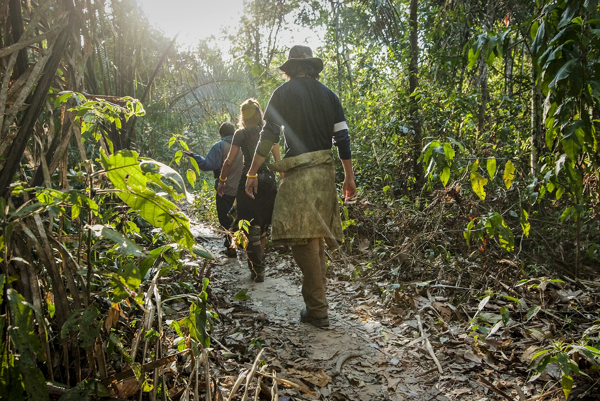 Features - A man and woman walk through the amazon rainforest during the mid morning.