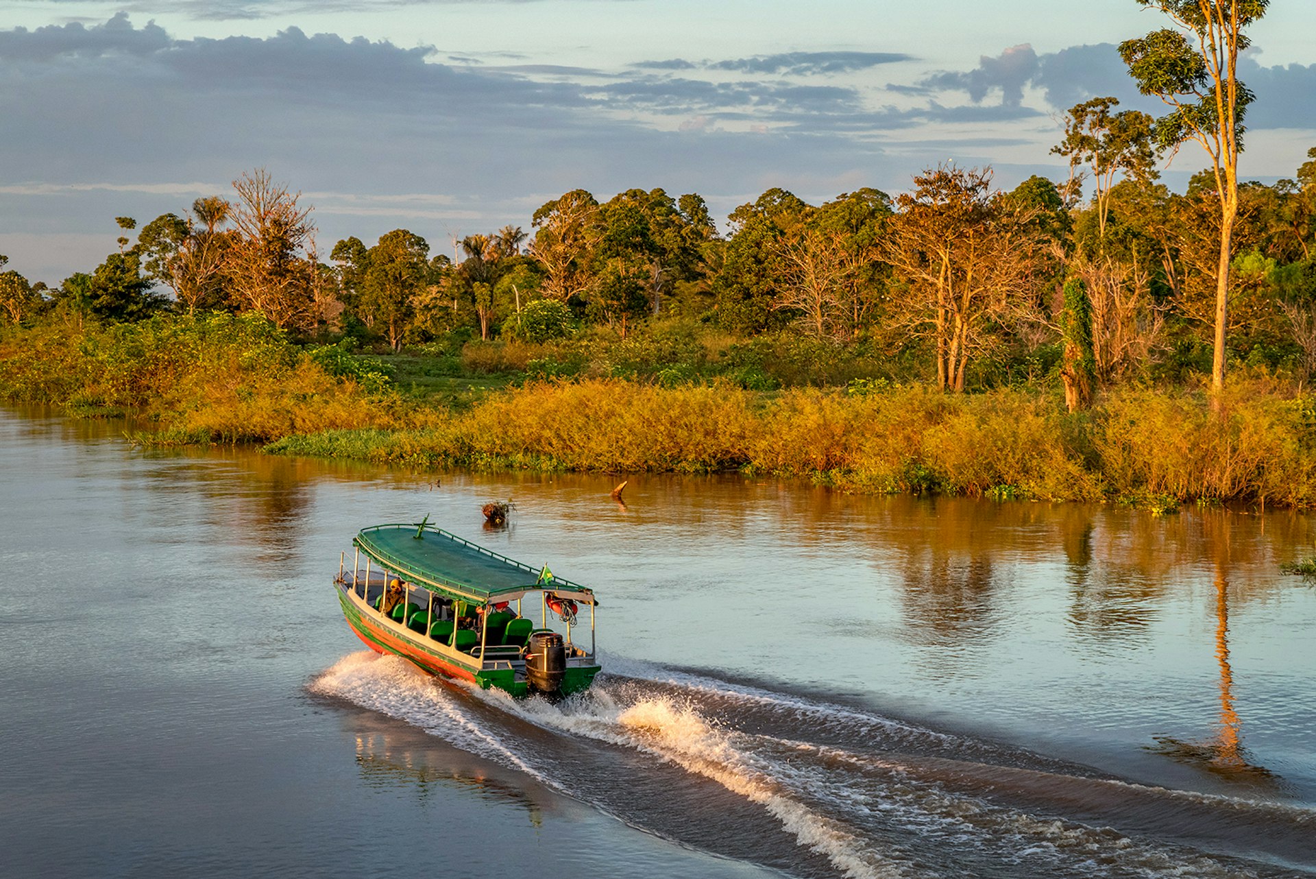A passenger riverboat cruises down the Amazon at sunrise