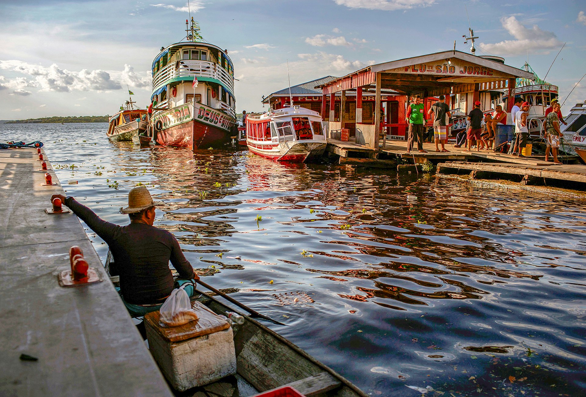 A man sits in a small fishing boat looking at the port in Tefe