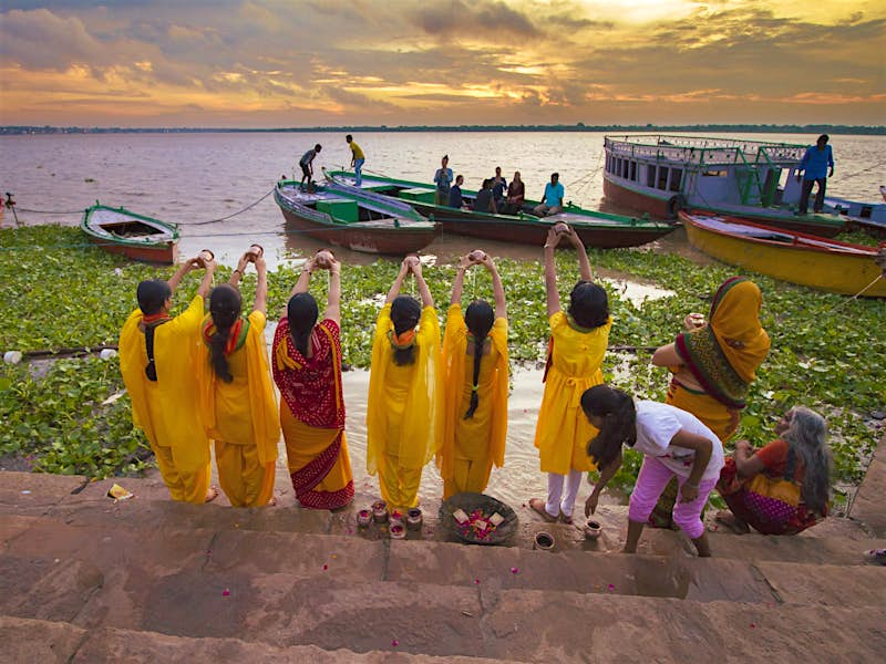 Women offer morning puja (prayers) beside the sacred river
