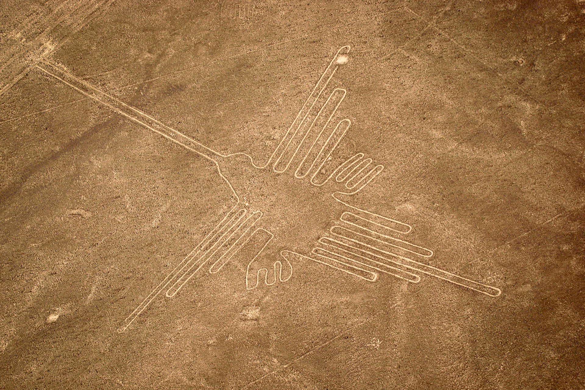 An aerial shot of a hummingbird carved into red dirt near Nazca