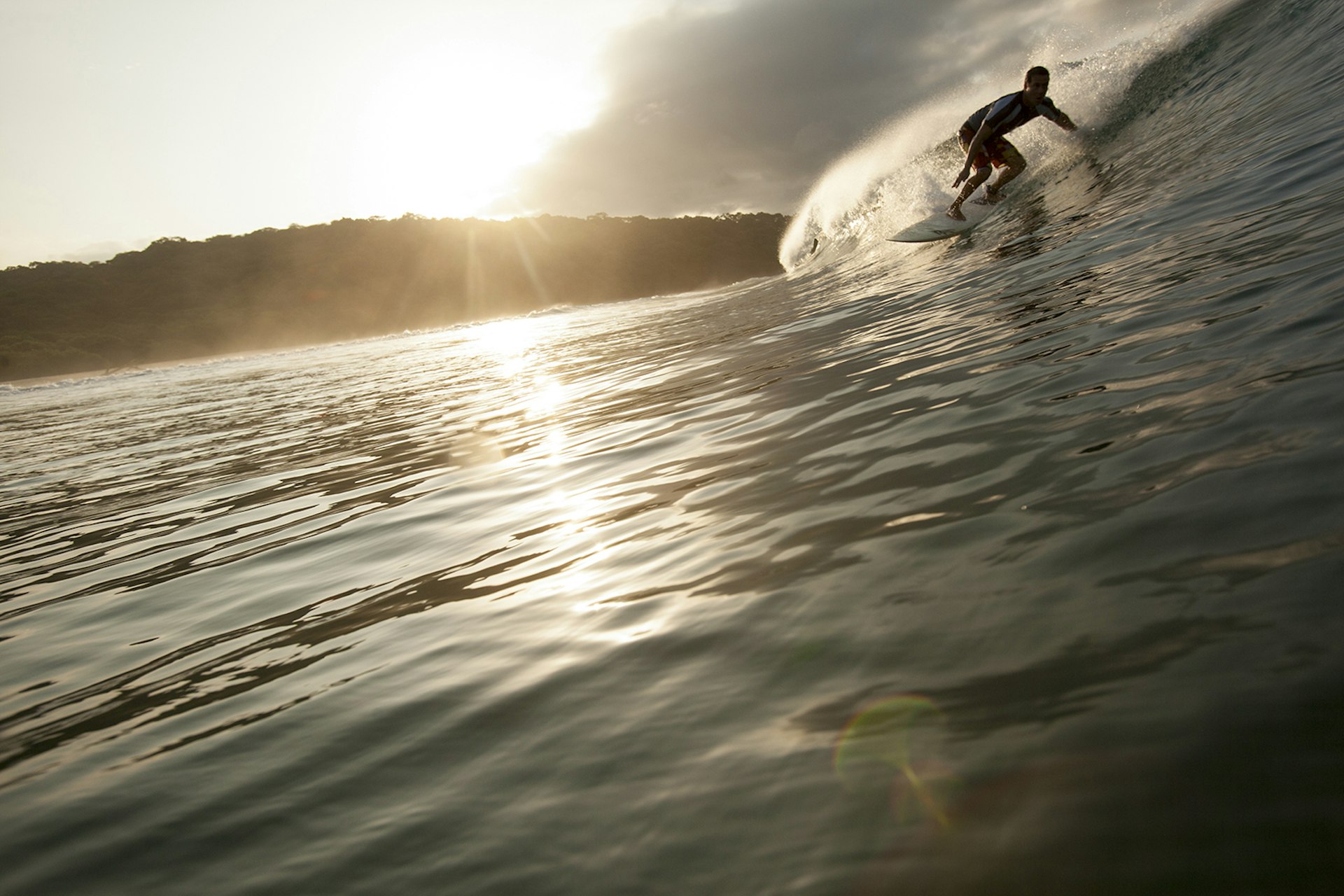 Features - A man Surfing down a barrel at sunset in Nicaragua